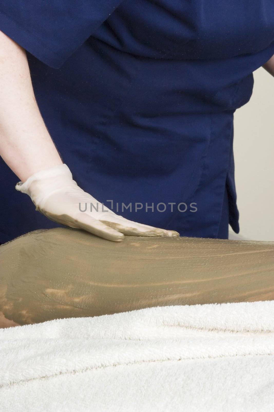 Sea mud for a full body wrap being applied to a leg a luxury spa.