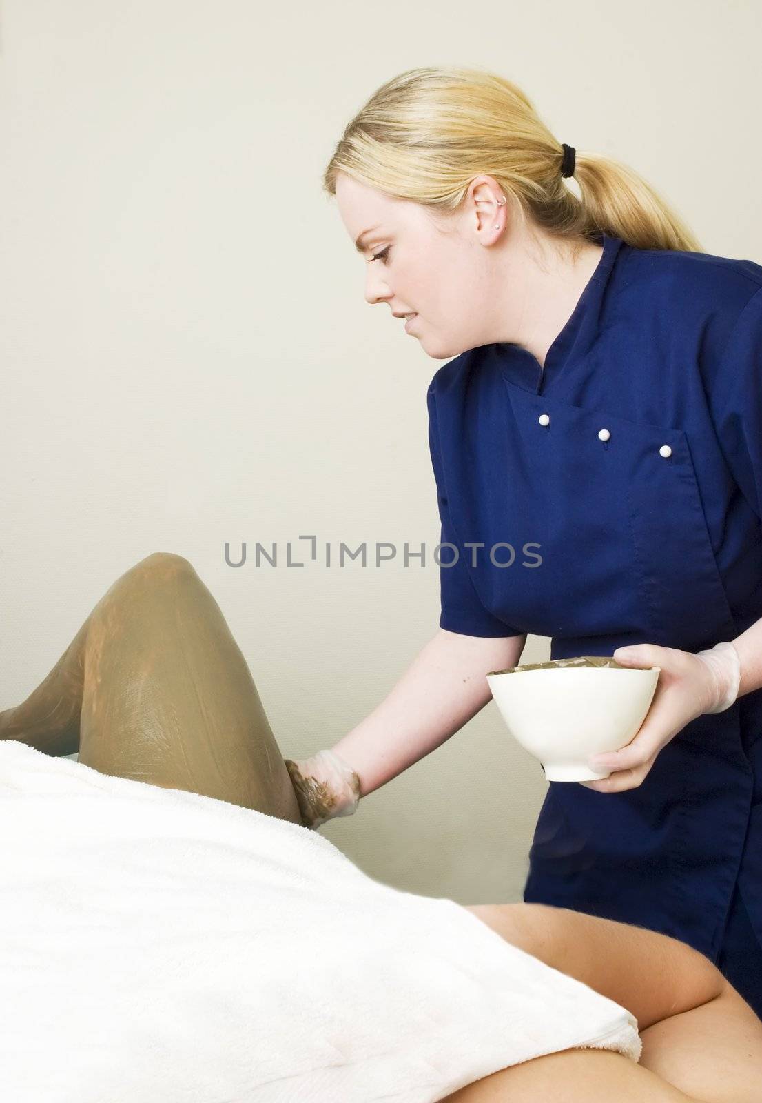 Sea mud for a full body wrap being applied to a leg a luxury spa.