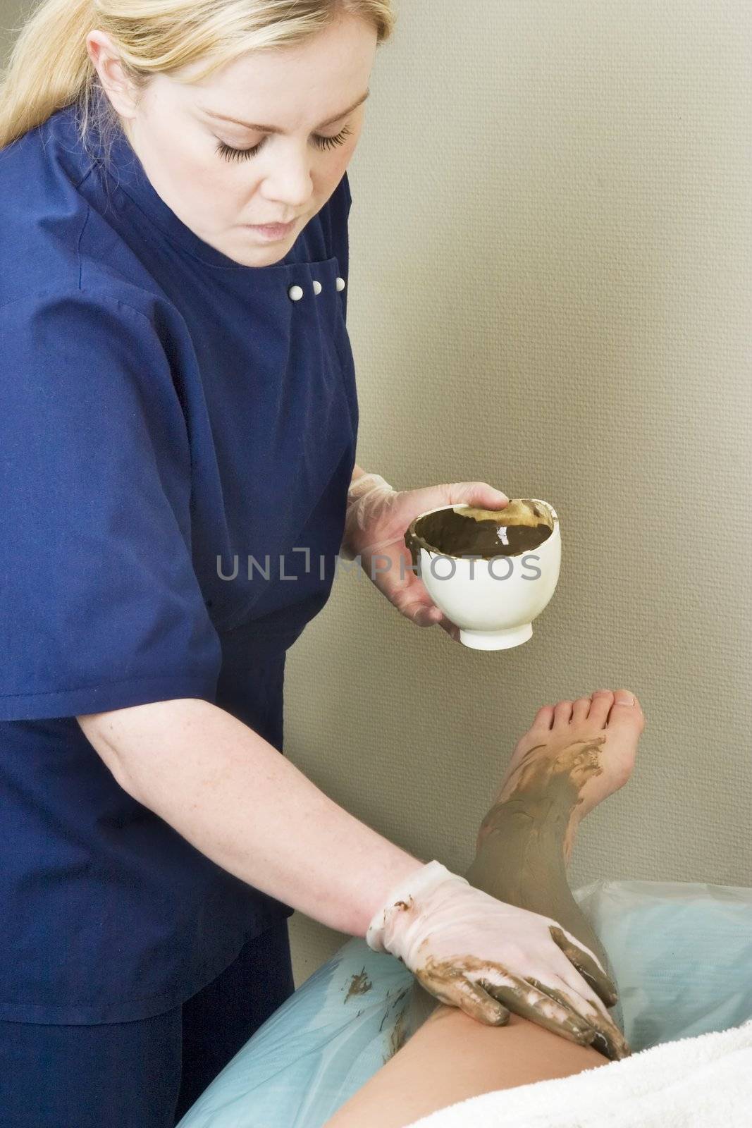 Sea mud for a full body wrap being applied to a leg a luxury spa.