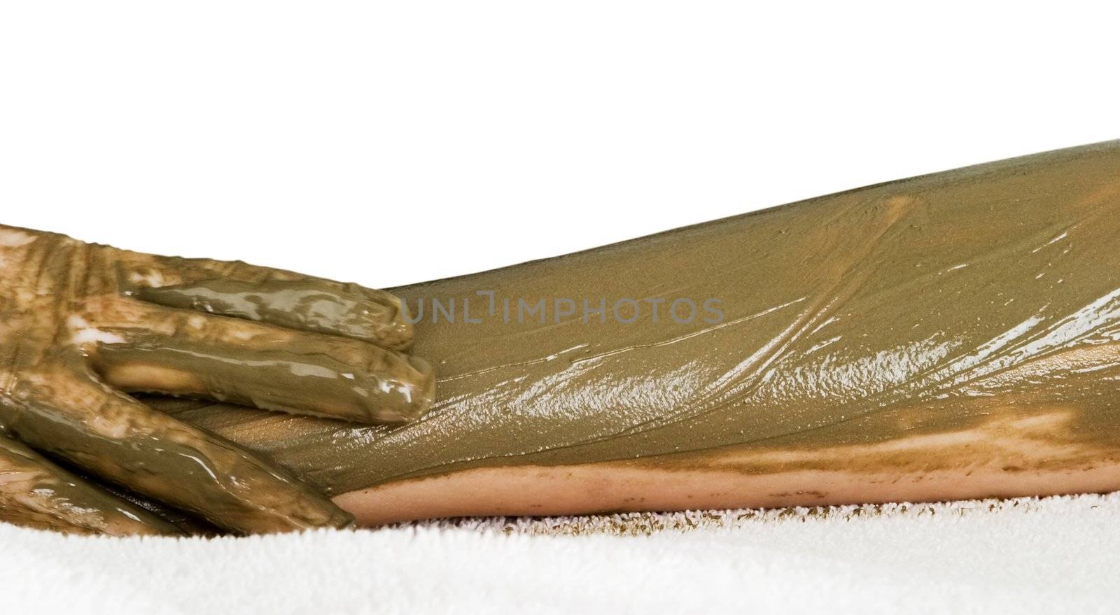A detail image of a sea mud full body wrap at a luxury spa being applied to the arm, with motion blur on the hand applying the mud pack.