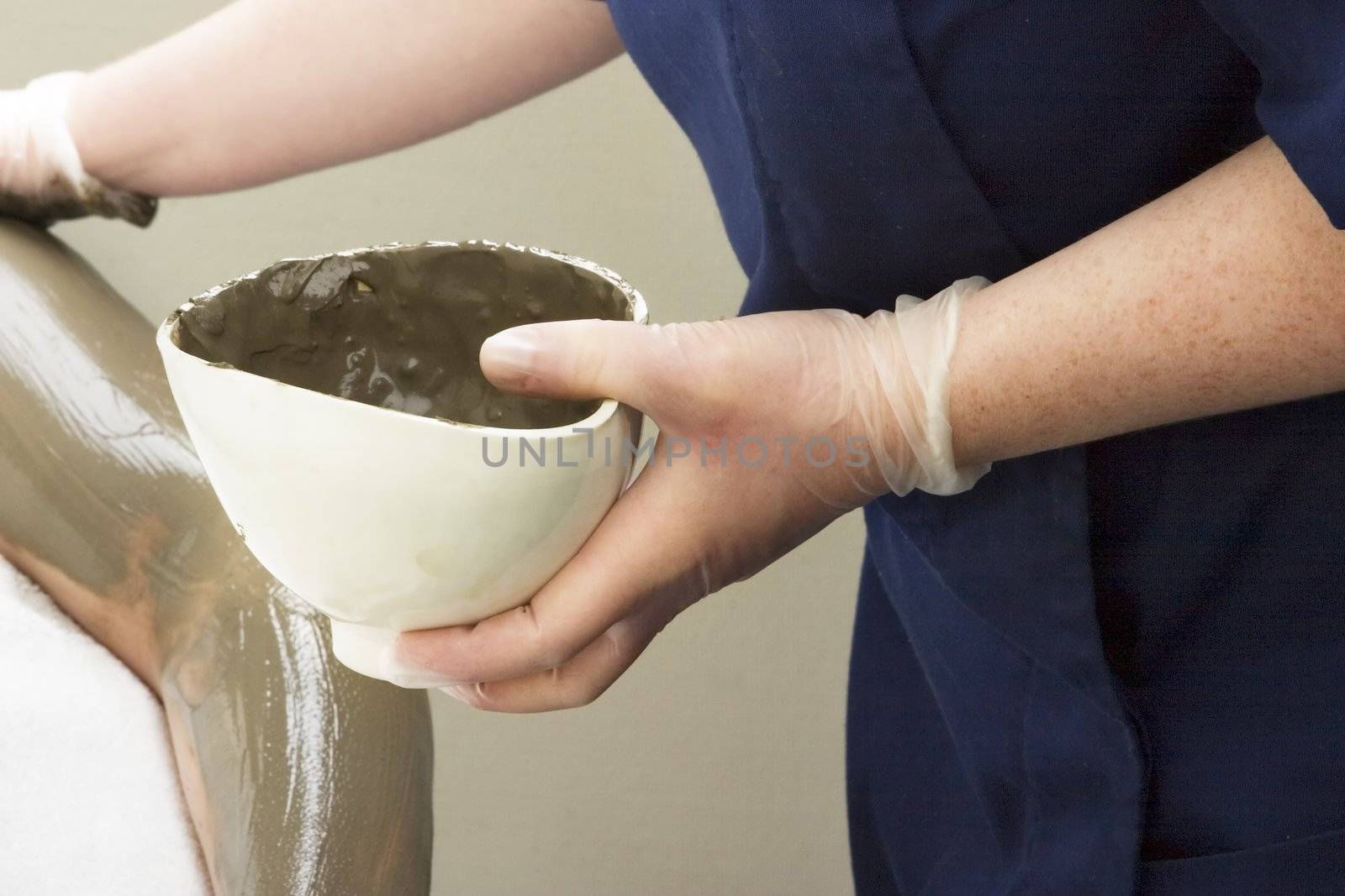 A detail image of a sea mud full body wrap at a luxury spa being applied to the arm.