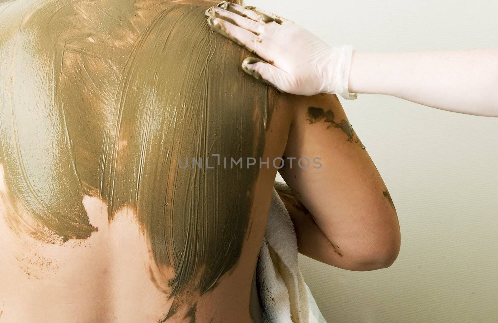 A sea mud full body wrap at a luxury spa being applied to the back and shoulders.