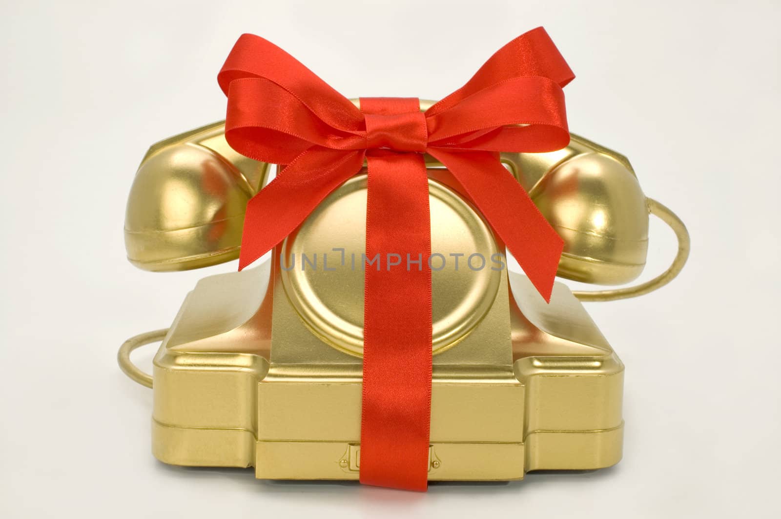 The telephone of gold colour with a red tape on a white background.
