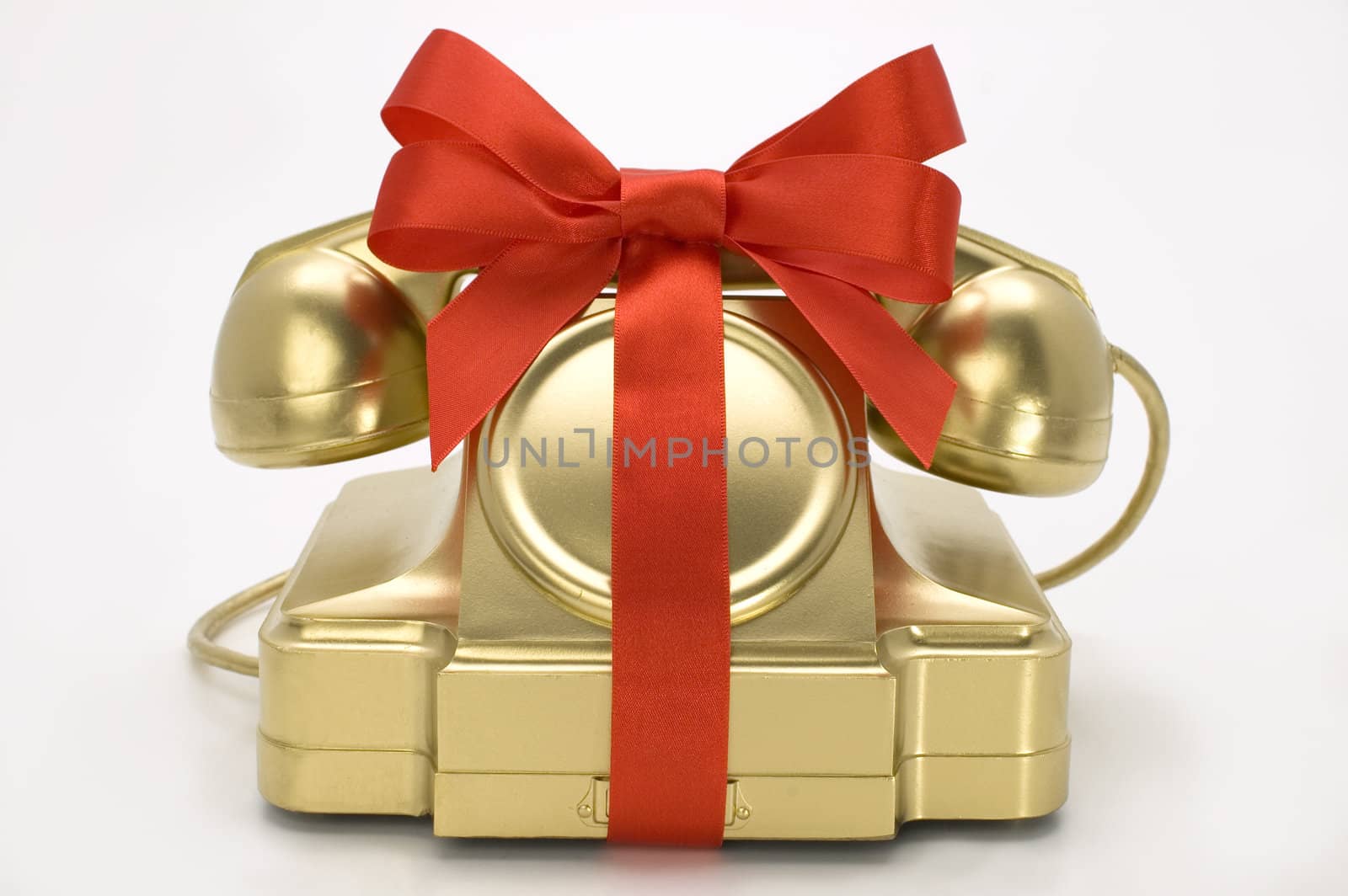 The telephone of gold colour with a red tape on a white background.