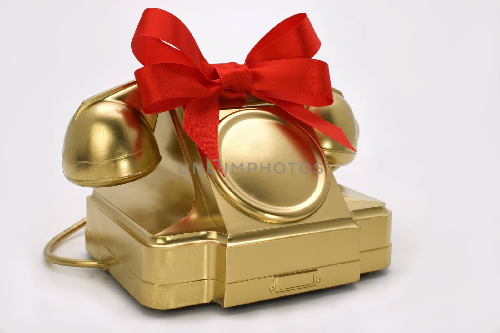 The telephone of gold colour with a red tape on a white background.