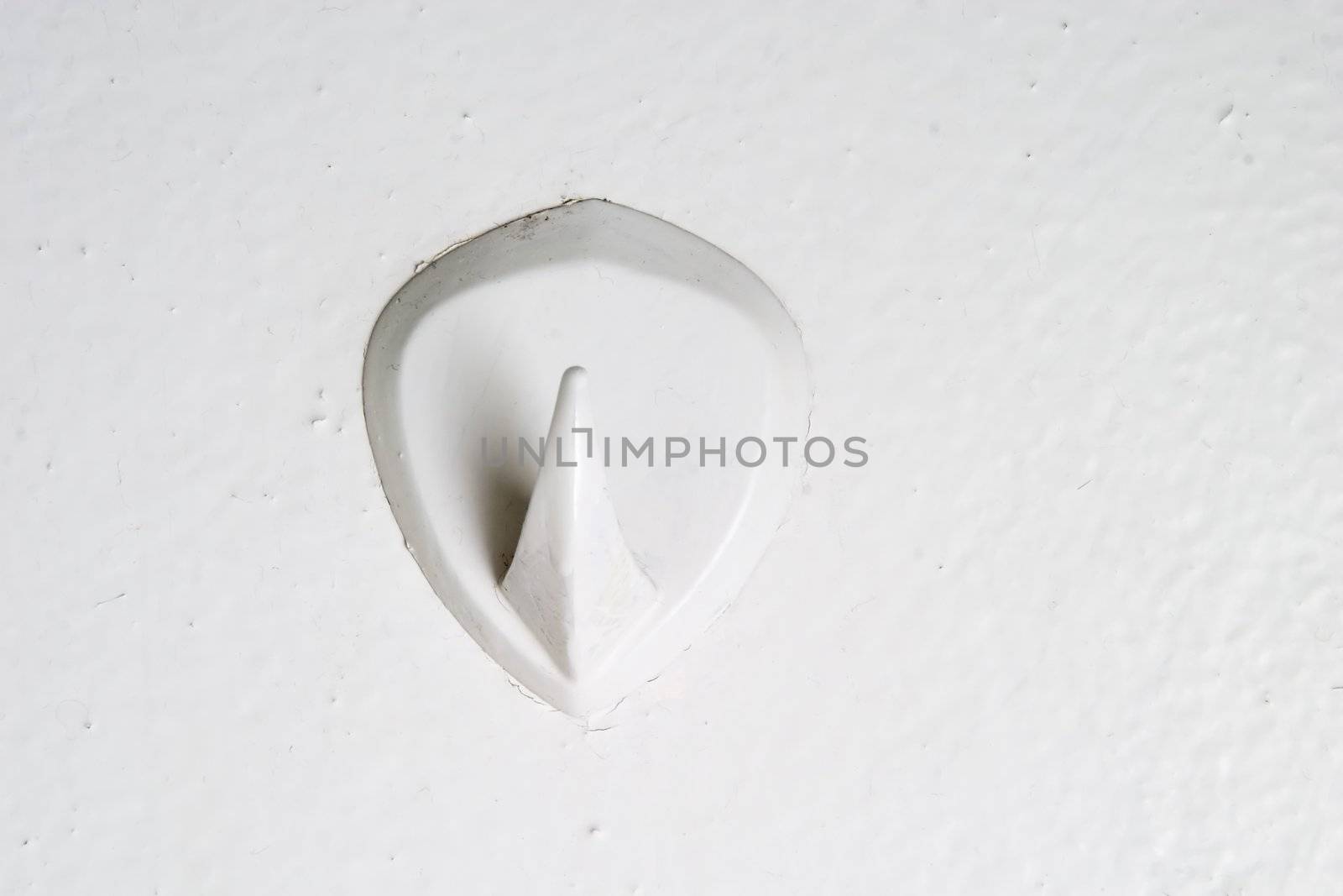 A retro bathroom hook stuck on the wall from the 1970's era.