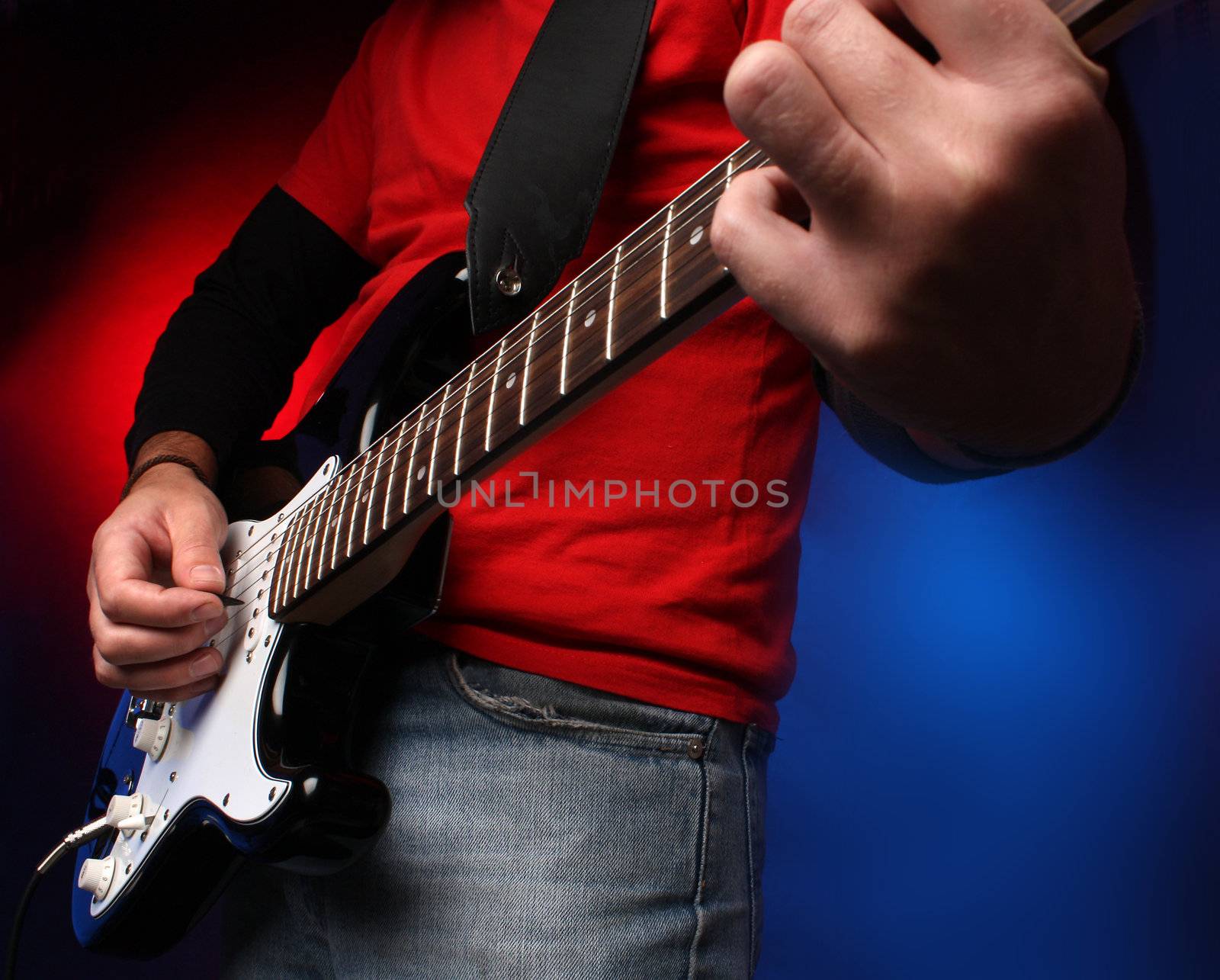 Detail of a musician playing a black electric guitar.