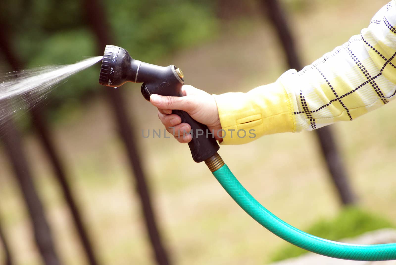 A woman uses the hose while she's outside.