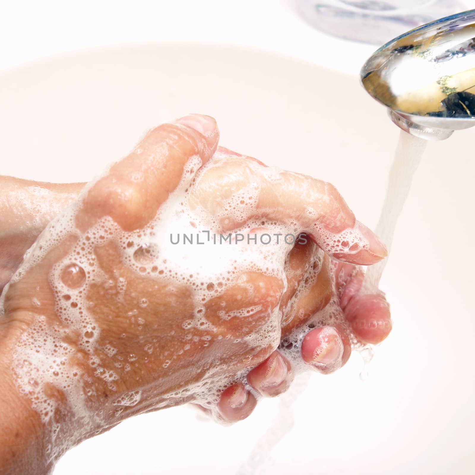 A woman washes her hands with soap and water.