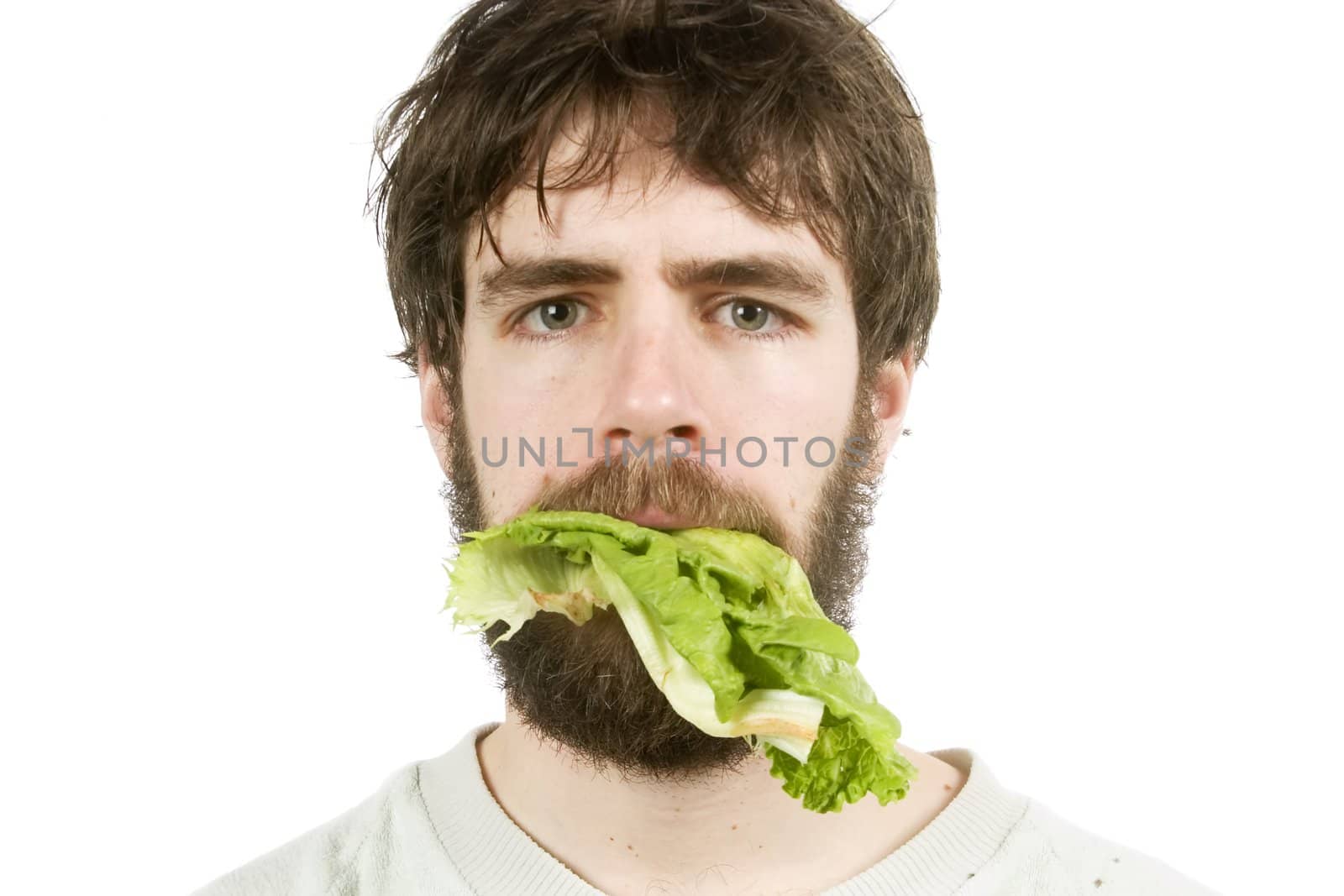 A young male with lettuce in his mouth, looking unimpressed.