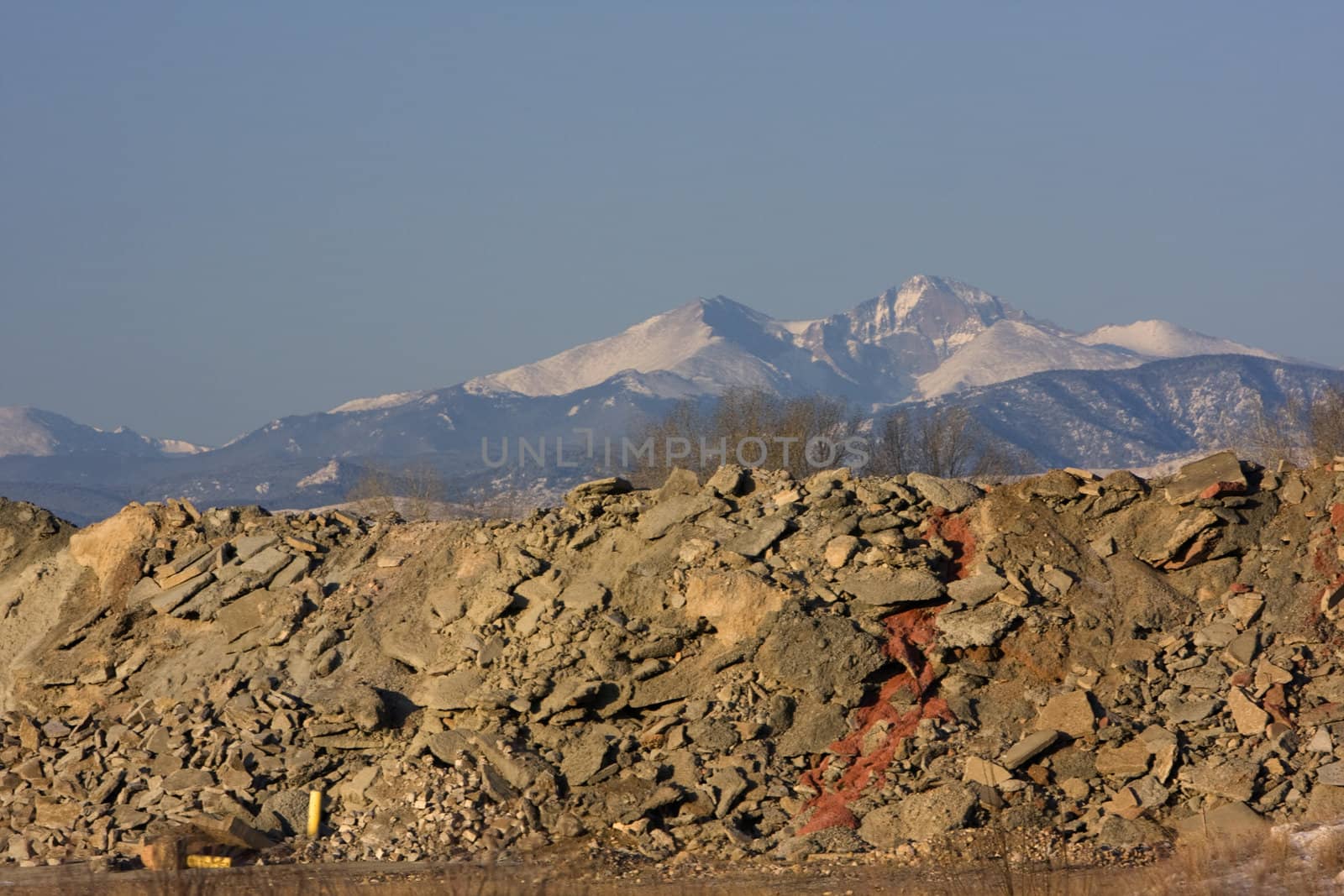 piles of concrete and construction waste obscure a view to snowy peaks of Rocky Mountains (Longs Peak in Colorado)