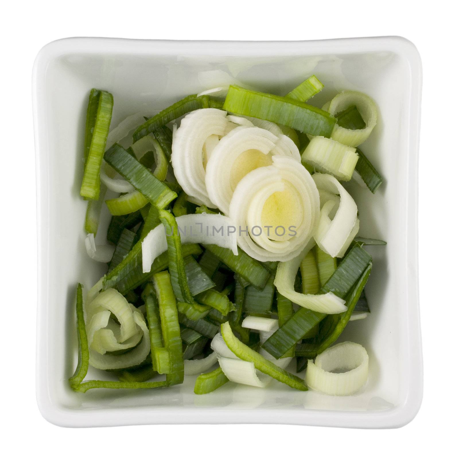 sliced leeks in a white square bowl, isolated with clipping path
