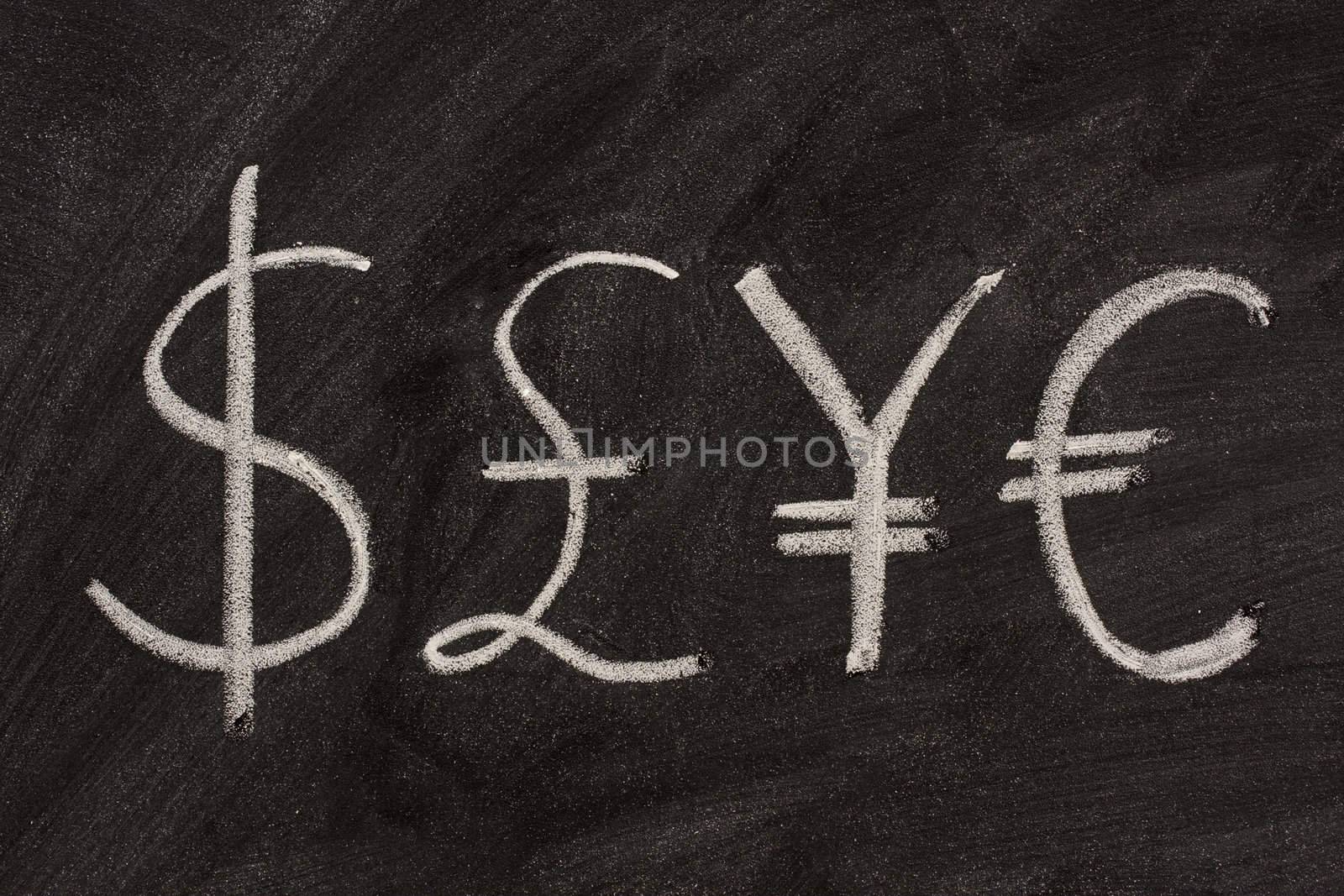 dollar, pound, yen and euro symbols sketched with white chalk on a black board