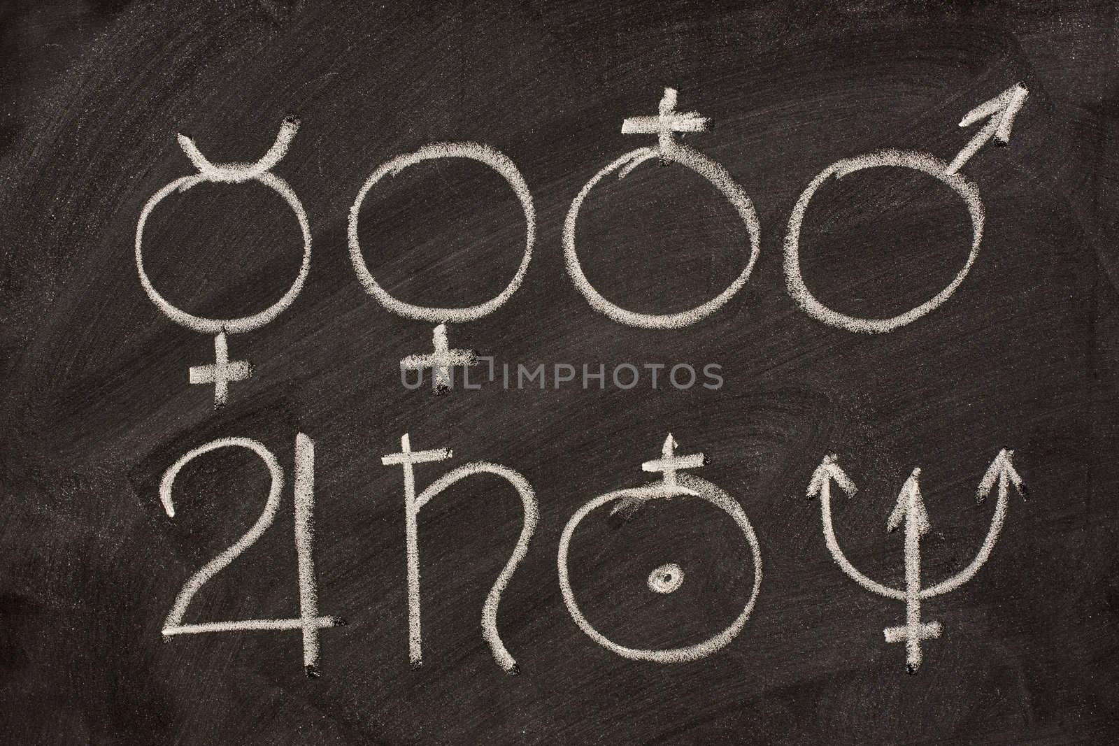 astronomical symbols for eight planets (Mercury, Venus, Earth, Mars, Jupiter, Saturn, Uranus, Neptune) sketched with white chalk on blackboard