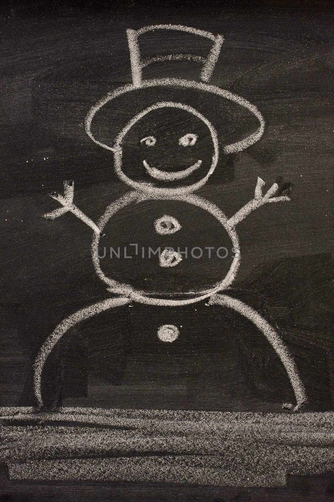 snowman sketched in a child style with white chalk on blackboard