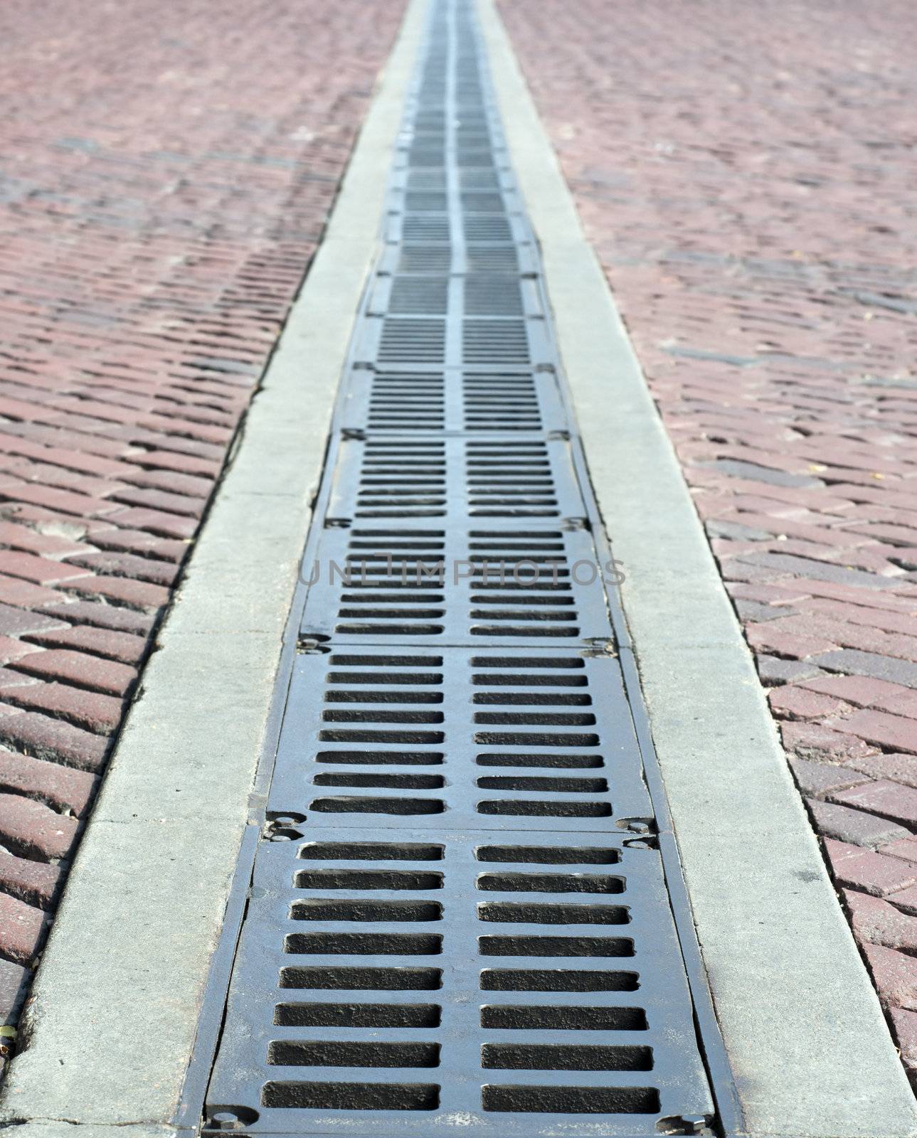 a brick road abtract blur with a metal grate drain down the center