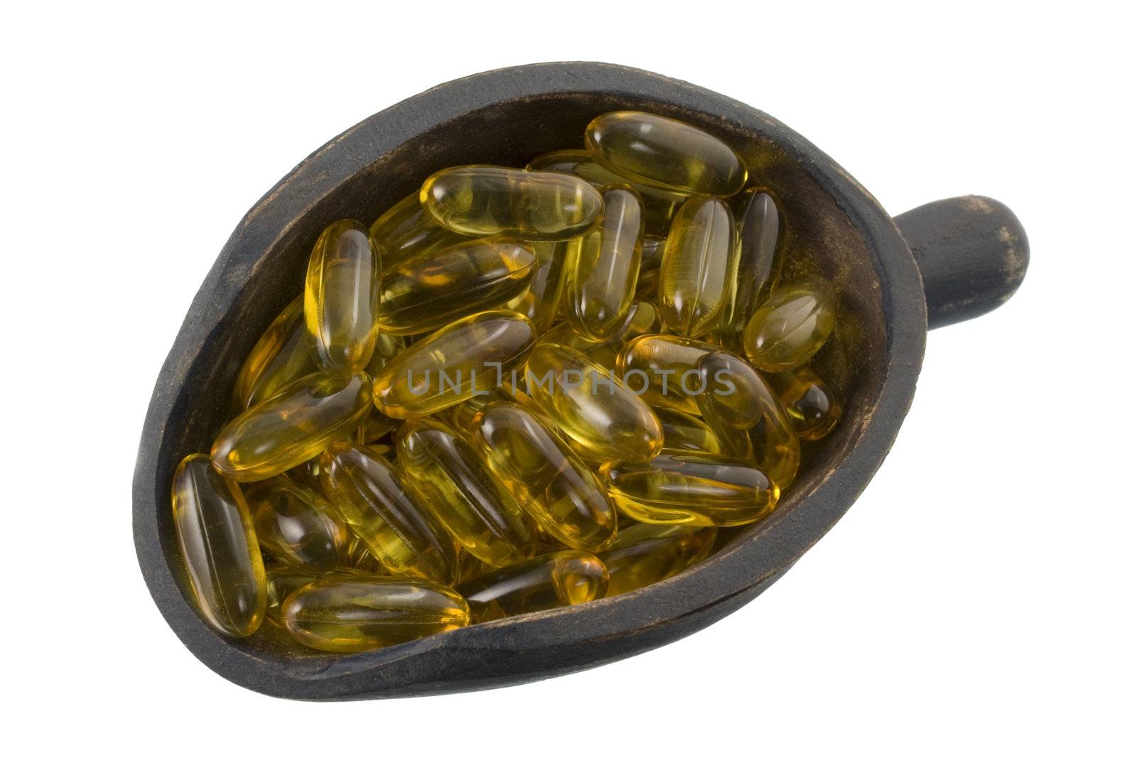 fish oil supplement softgels on a primitive, wooden, dark painted scoop, isolated on white
