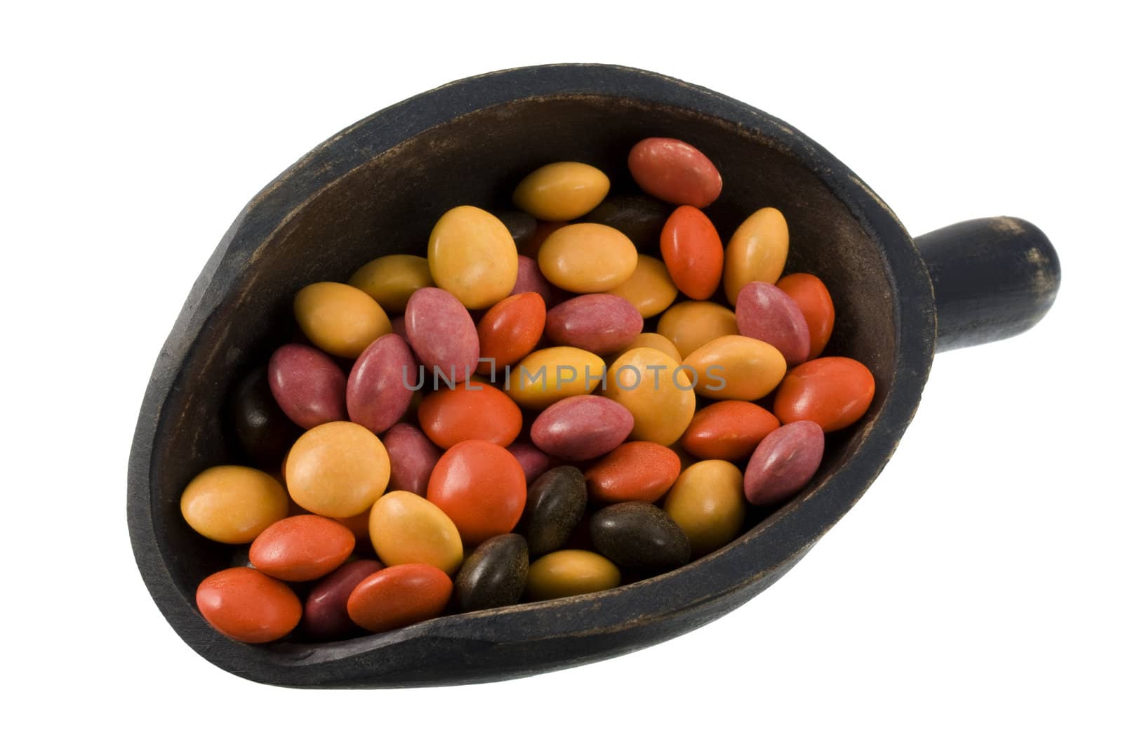 colorful coated chocolate candies on a primitive, wooden, dark painted scoop, isolated on white