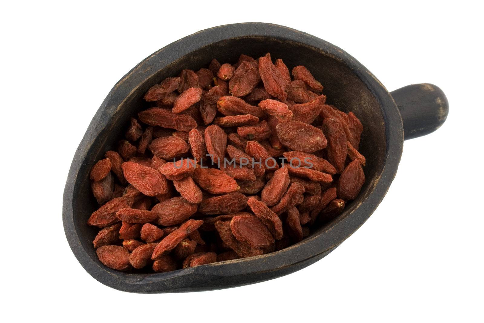 dried Tibetan goji berries (wolfberries) on a primitive, wooden, dark painted scoop, isolated on white