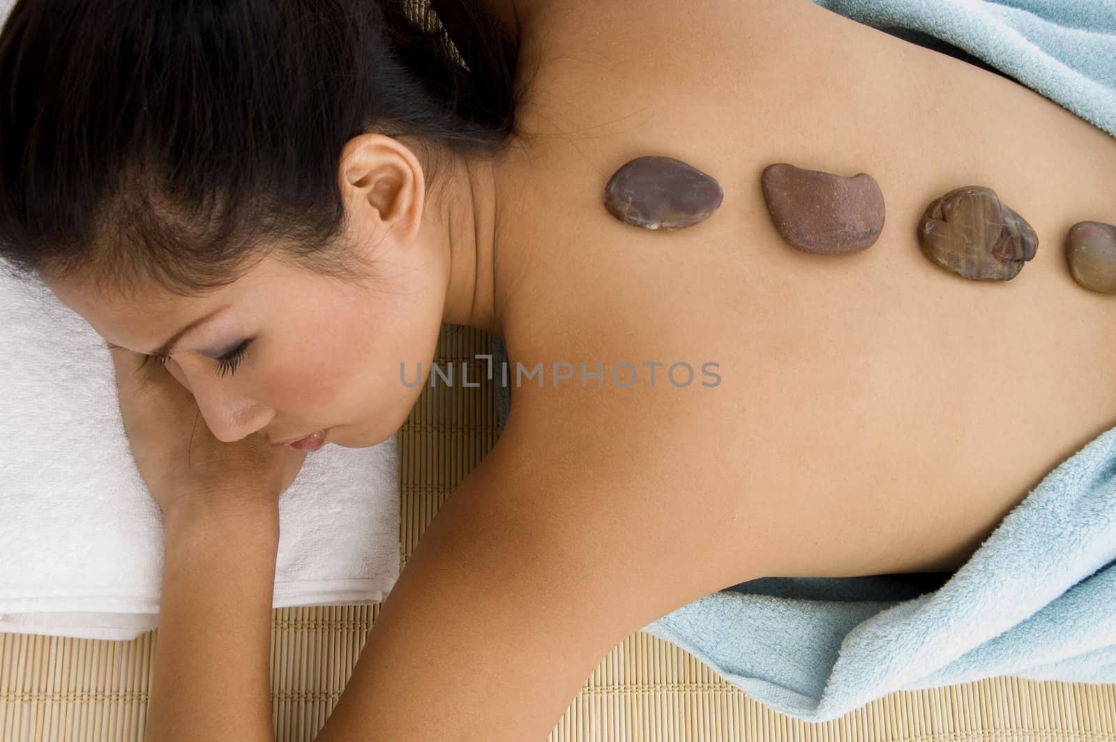 high angle view of laying young female taking stone therapy