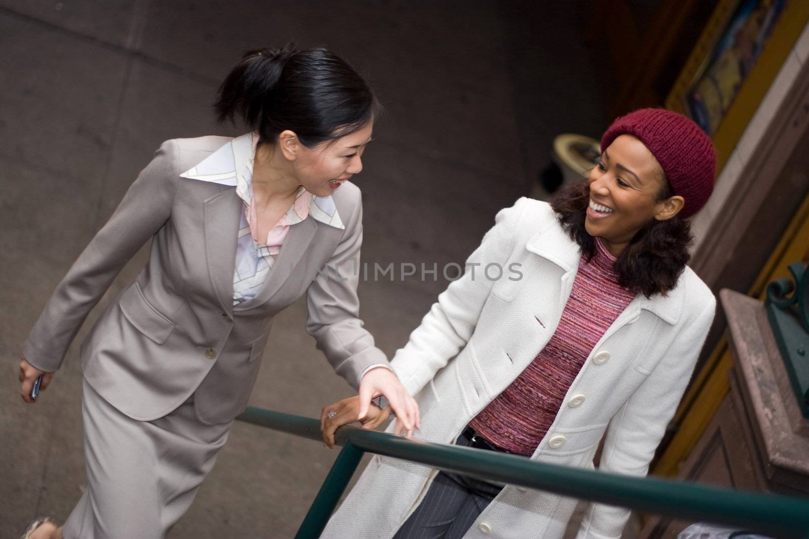 Two business women having a casual meeting or discussion while walking in the city.  