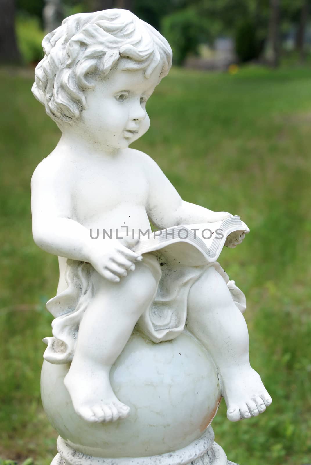 A closeup of a statue of a small boy reading a book.