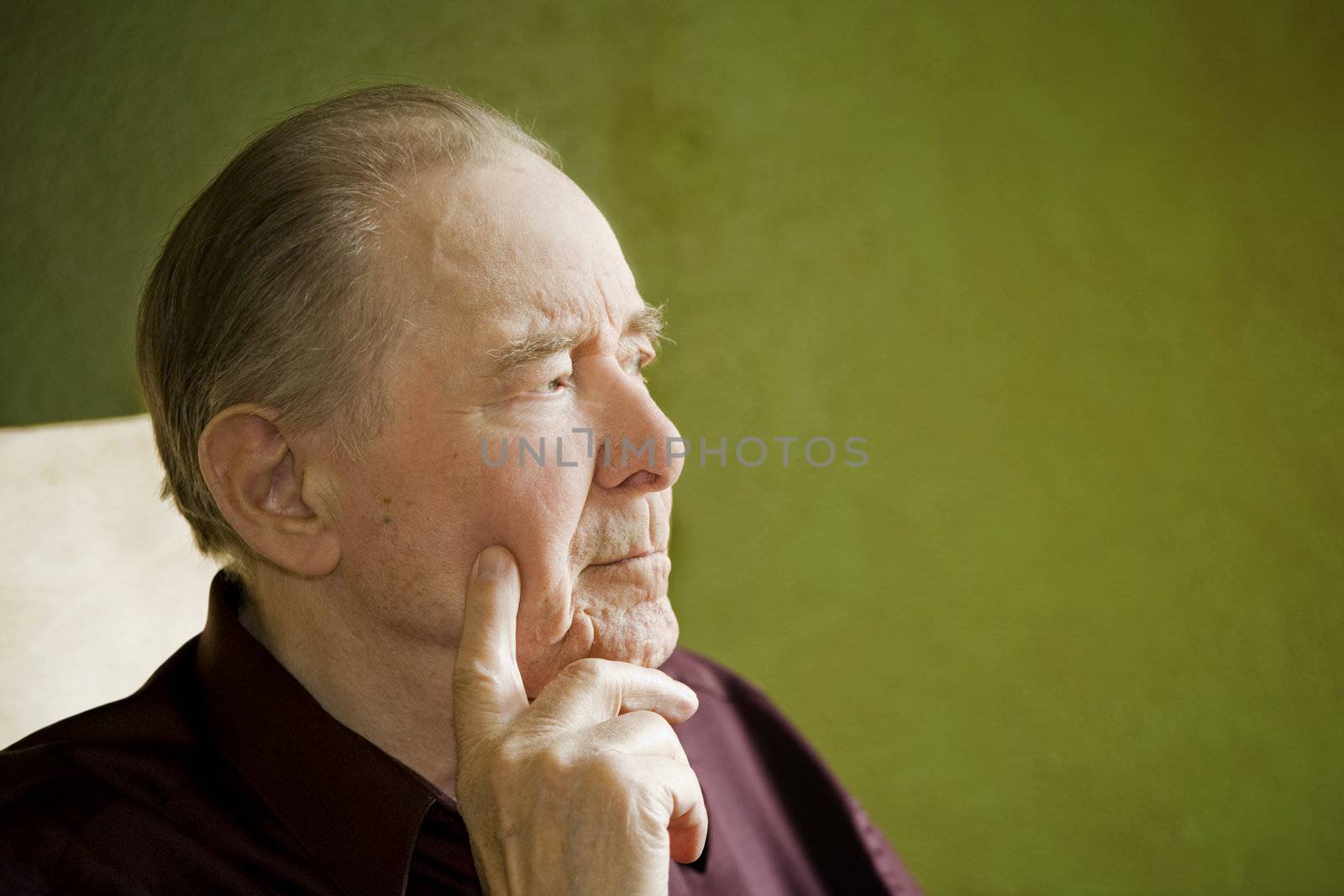 Elderly man in rocking chair looking out sunny window