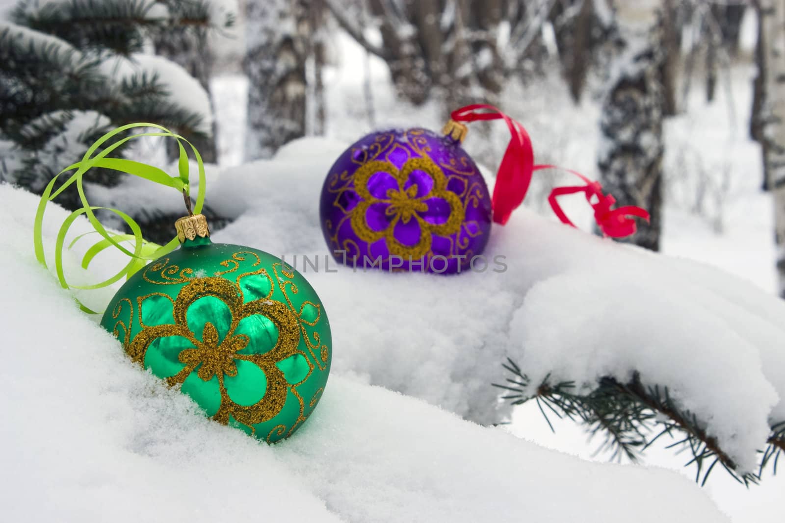 Two color christmas baubles sitting in a bed of snow.