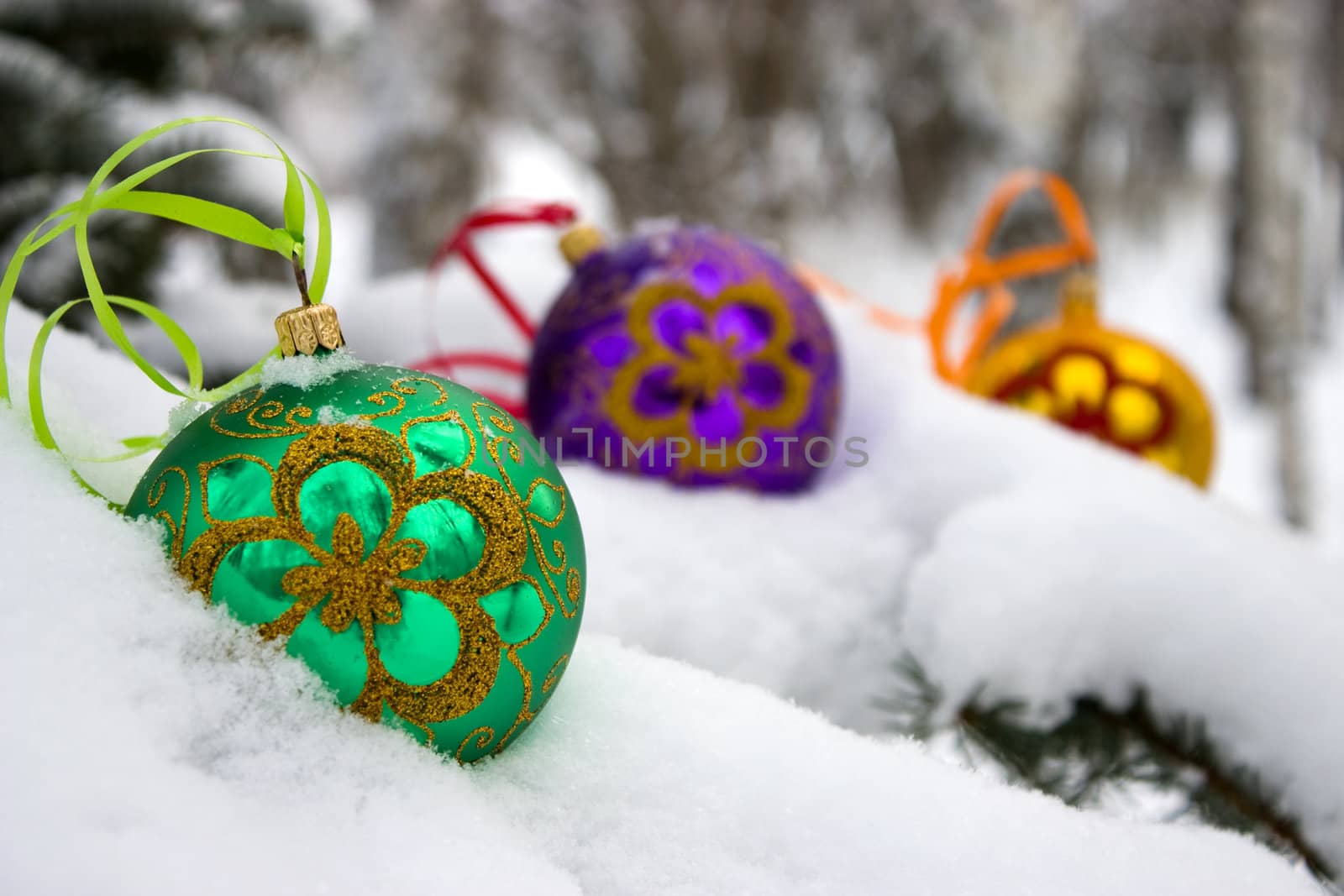 Three color christmas baubles sitting in a bed of snow.