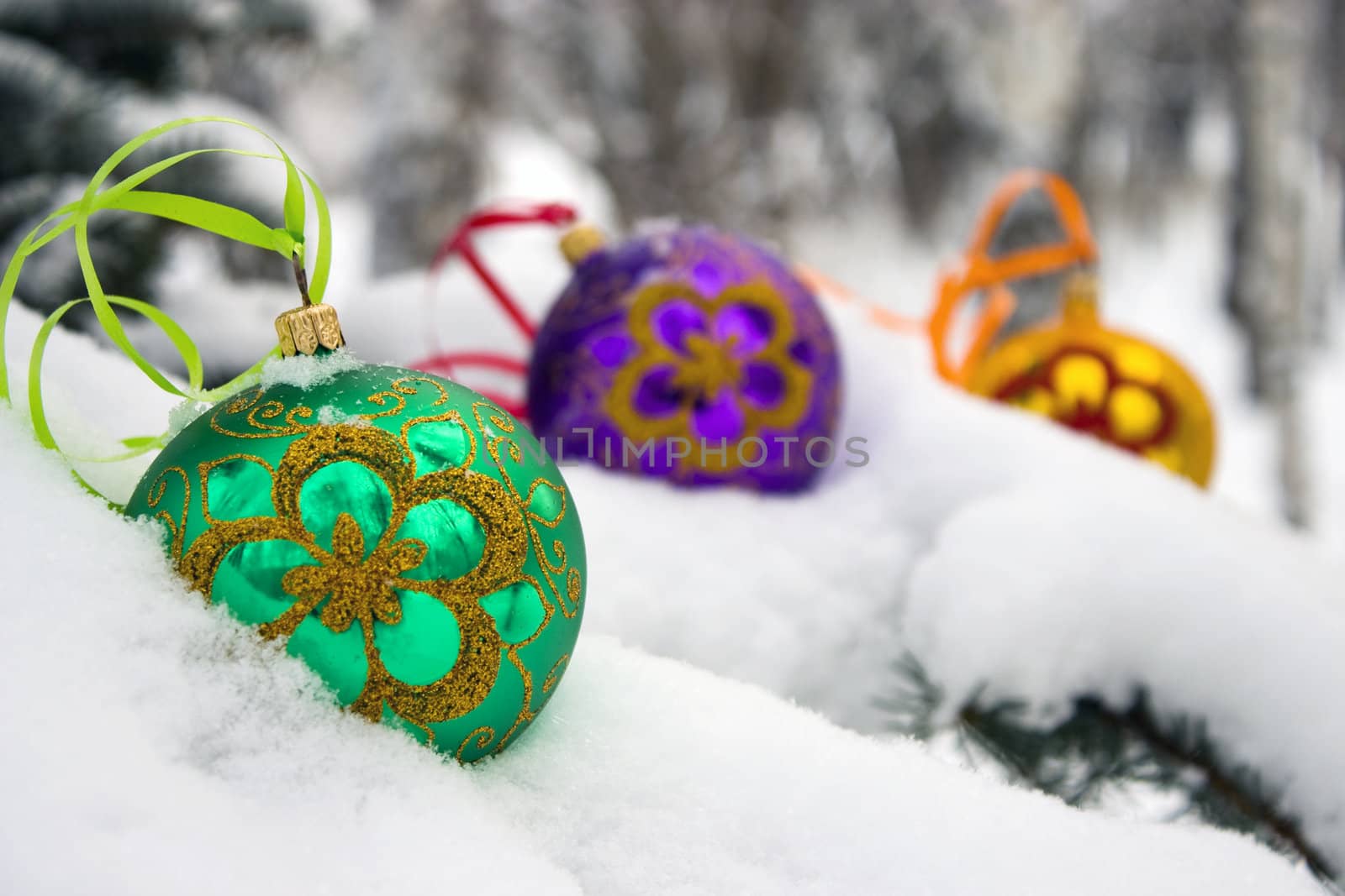 Three color christmas baubles sitting in a bed of snow.