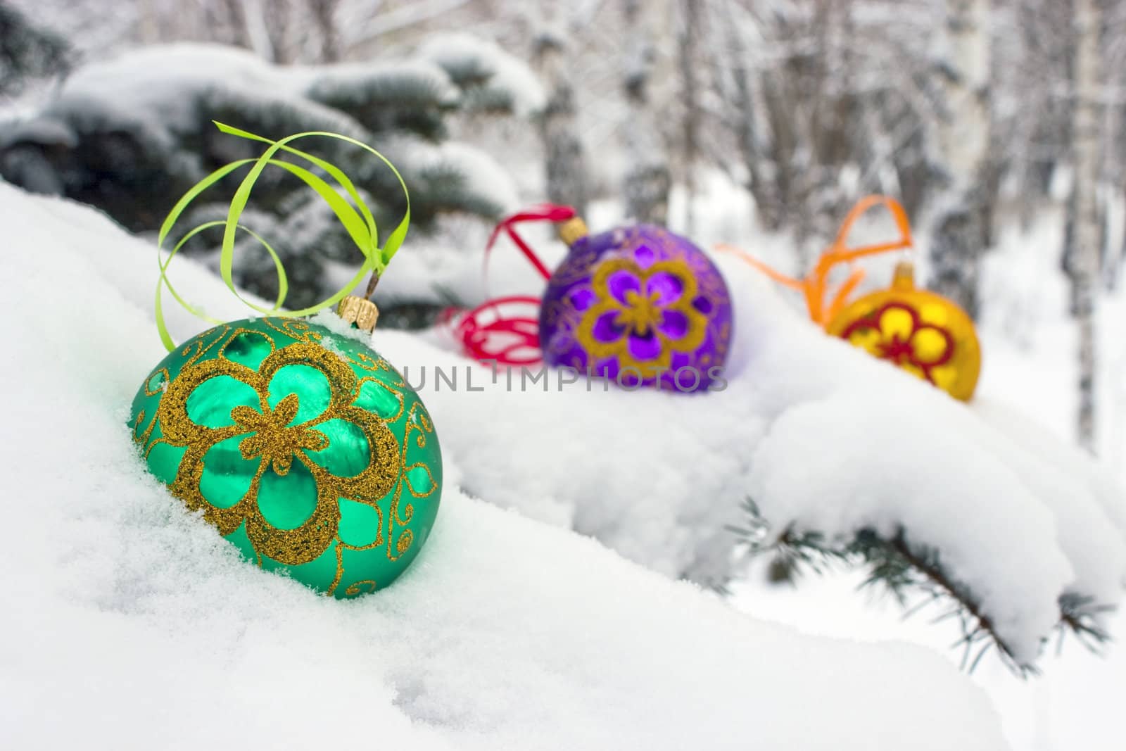 Three color christmas baubles sitting in a bed of snow.