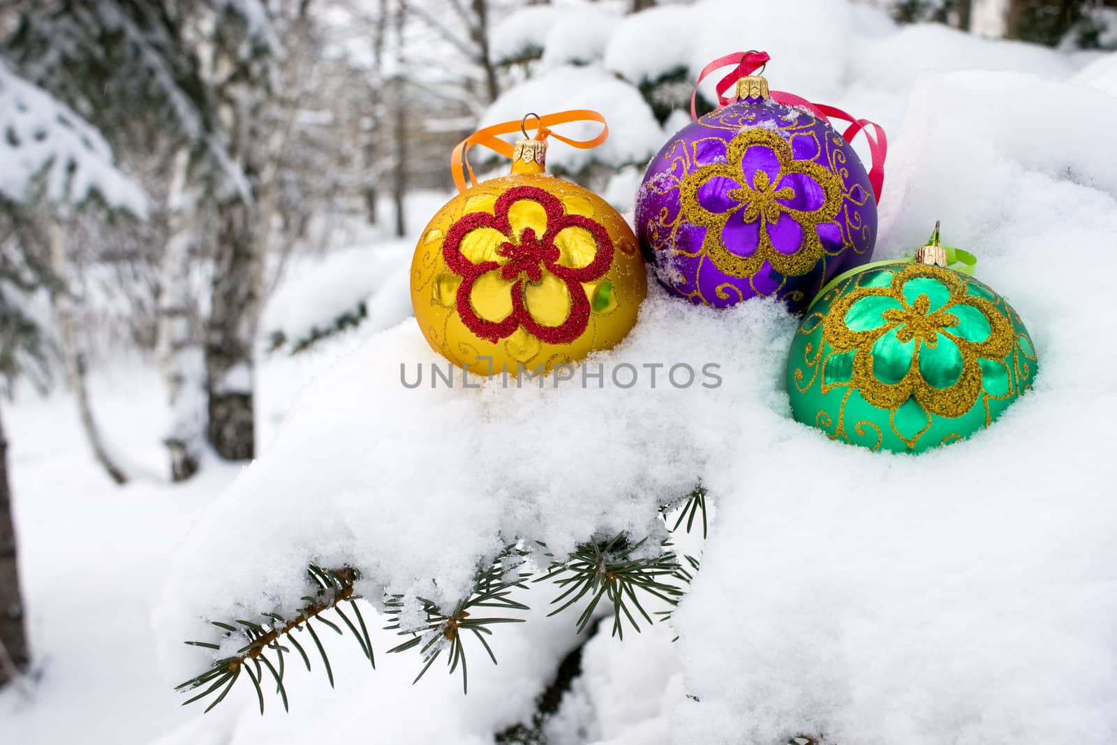 Three color christmas baubles sitting in a bed of snow.