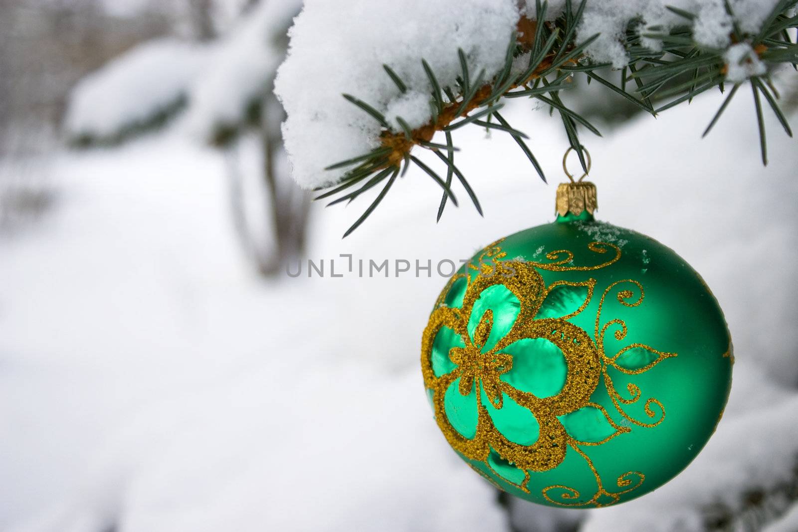 Green  christmas glass ball hanging on the tree in snow.