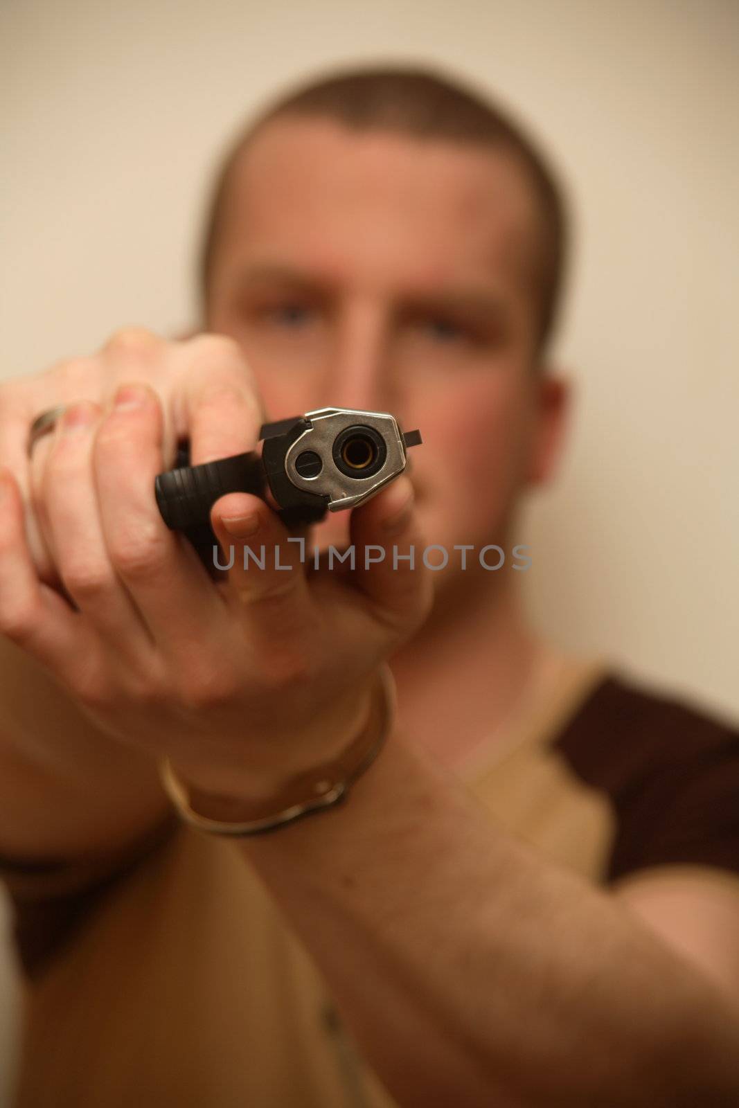 A young man holding a pistol towards the camera.