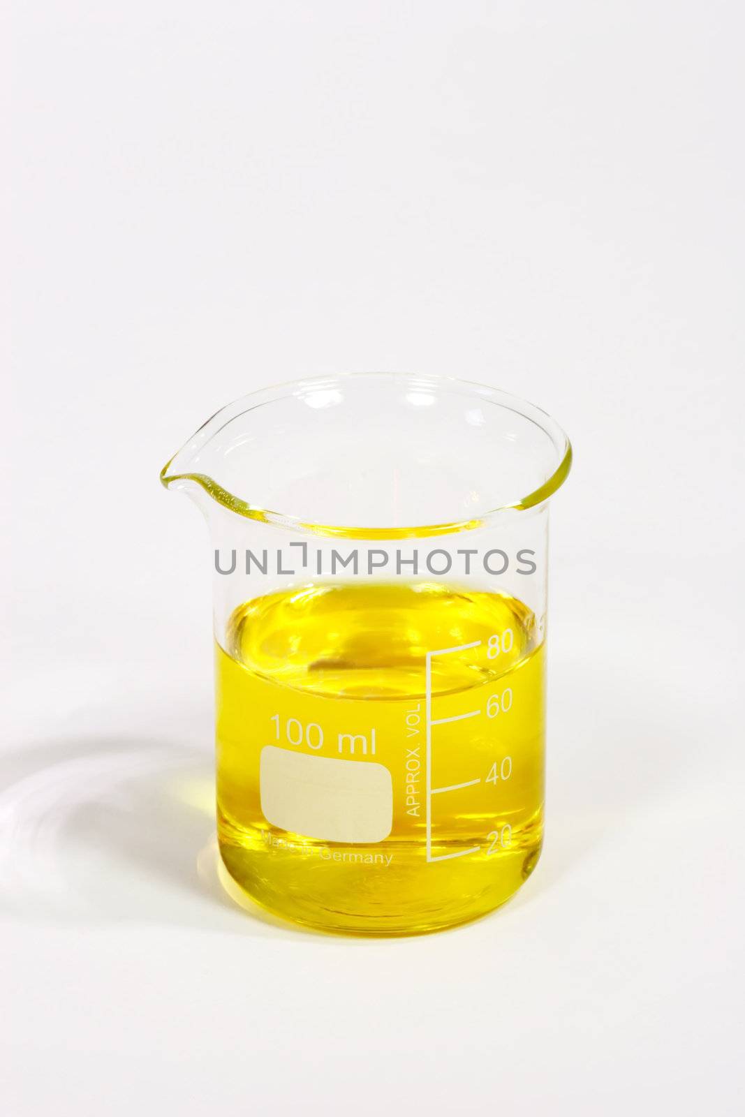 Graduated beaker with yellow fluid on bright background