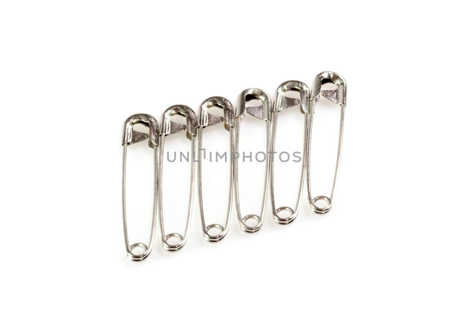 Six silver safety pins on white background