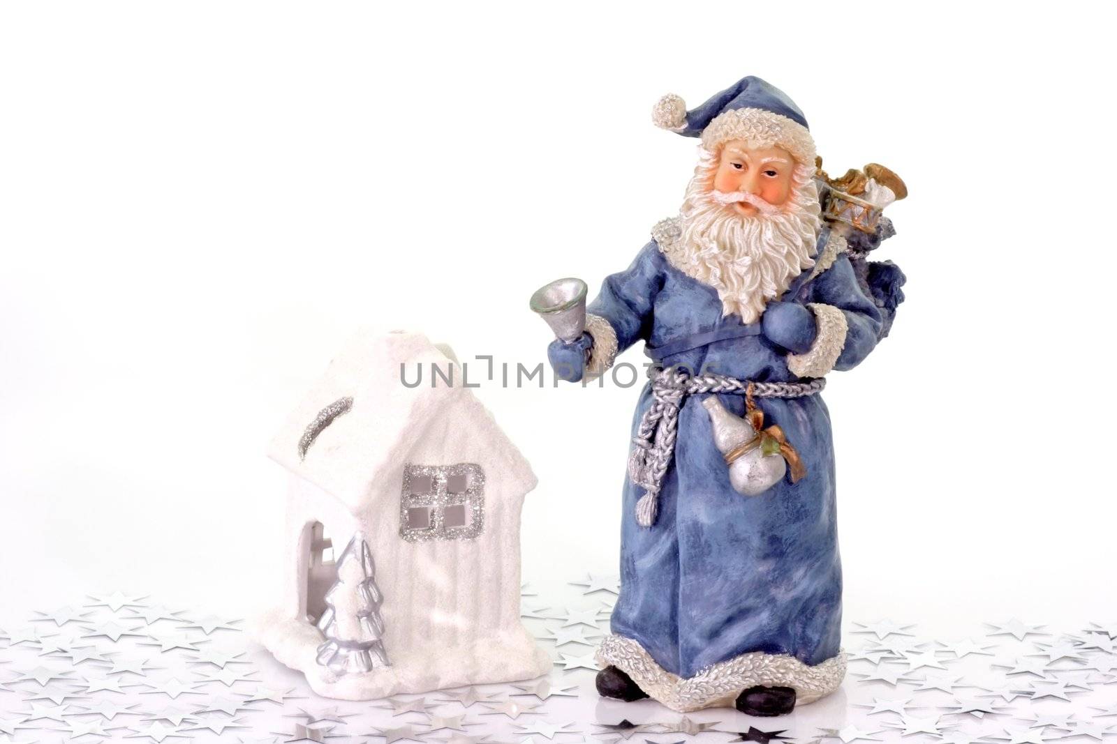 Blue Santa Claus figure with white ceramic house and silver stars on light background