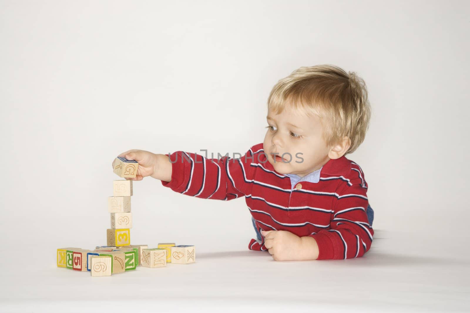 Studio portrait of Caucasian boy playing with toy blocks.