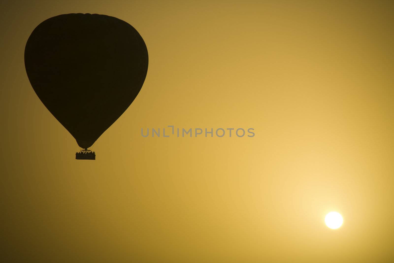 A hot air Balloon backlit by the rays of the morning Sun.