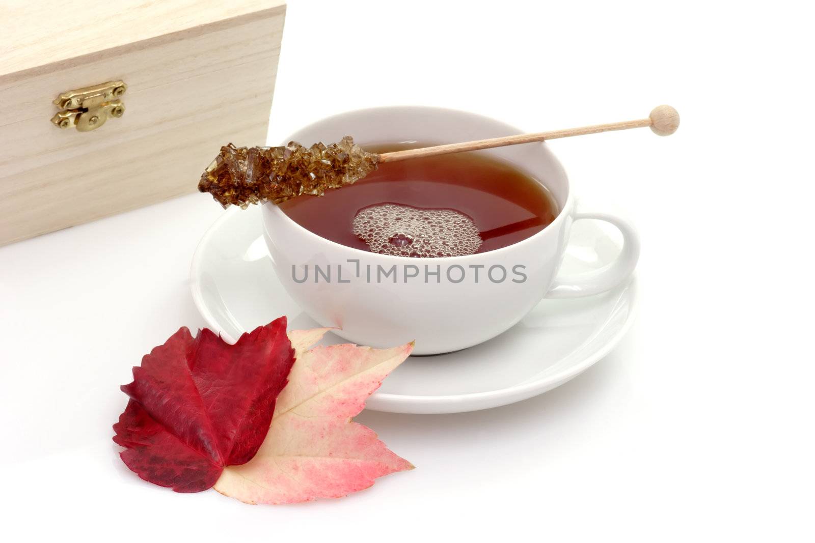 A cup of tea with autumn foliage on bright background