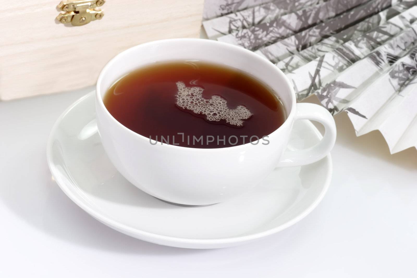 A cup of tea with fan and wooden box on bright background