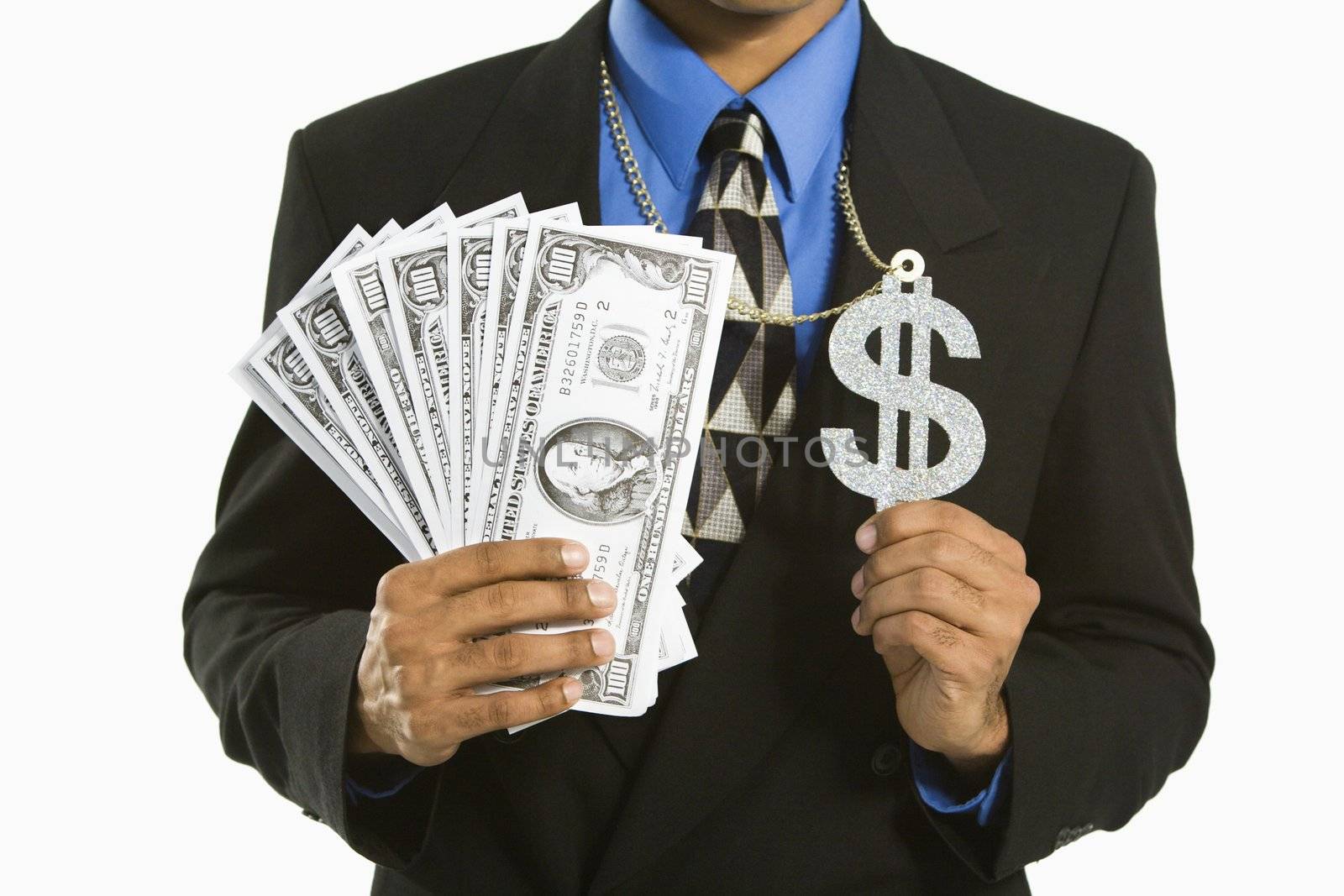 African American man in suit wearing necklace with money sign and holding cash.