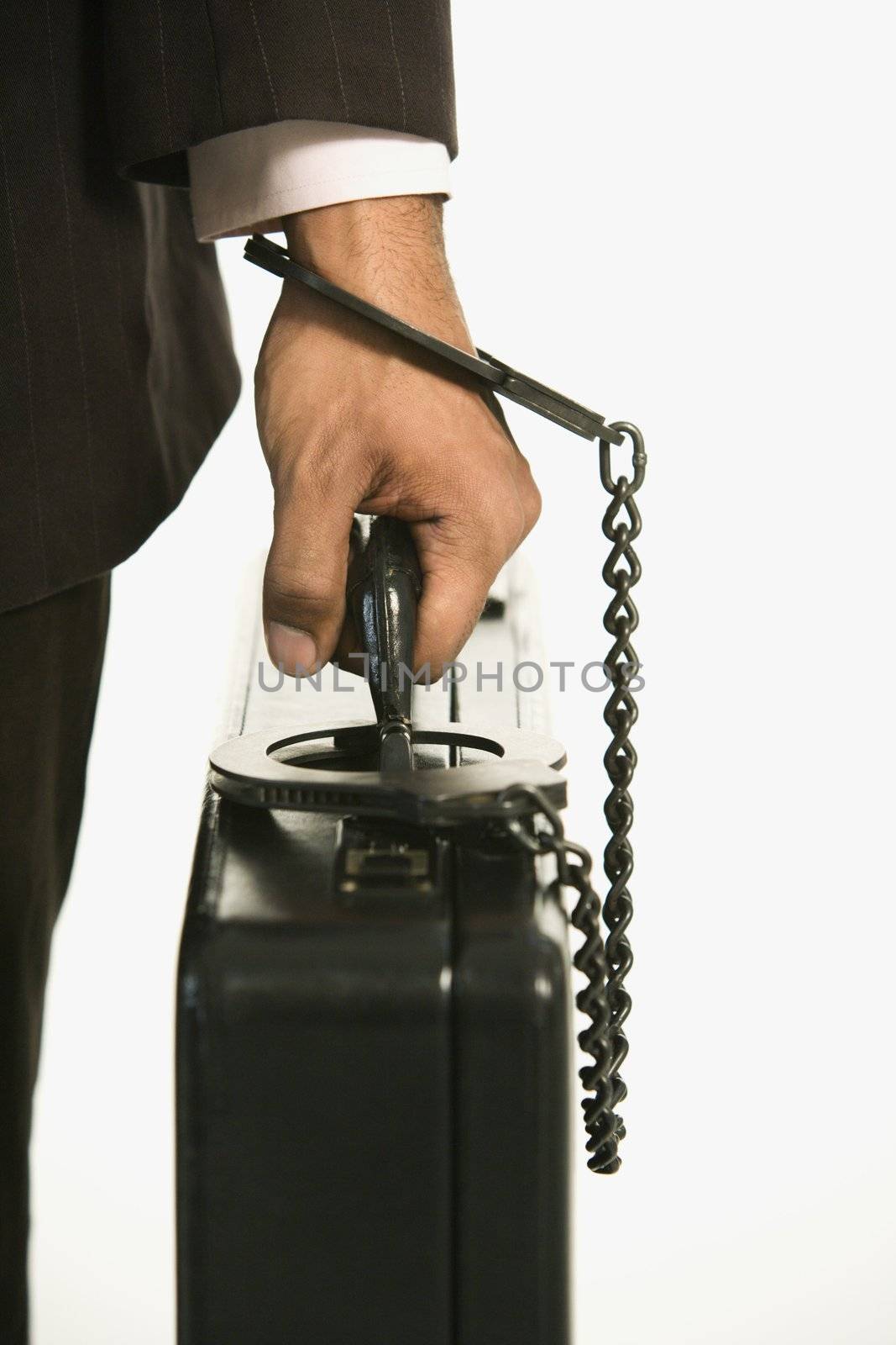 African American businessman in suit handcuffed to briefcase.