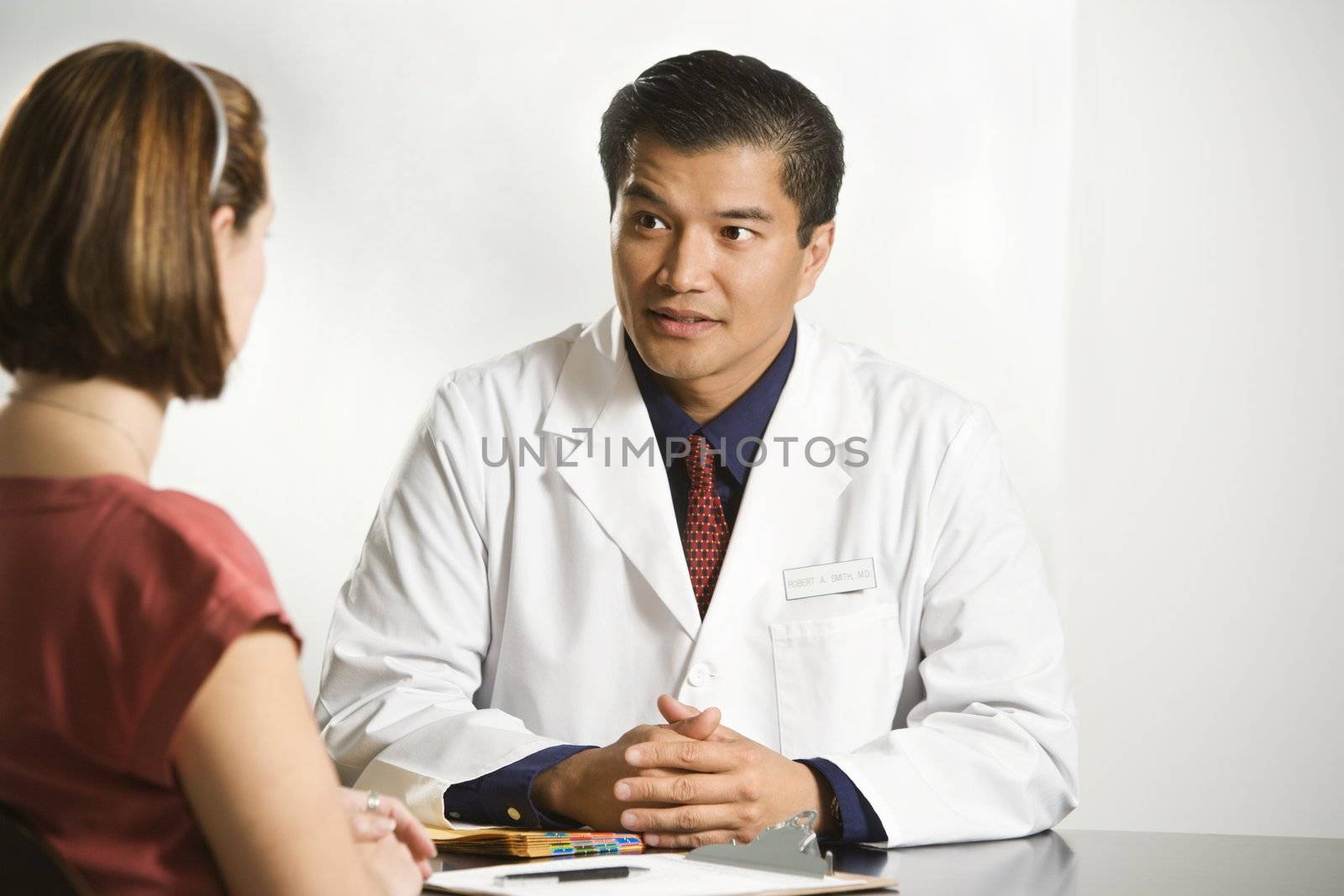 Asian American male doctor consulting with Caucasian female patient.