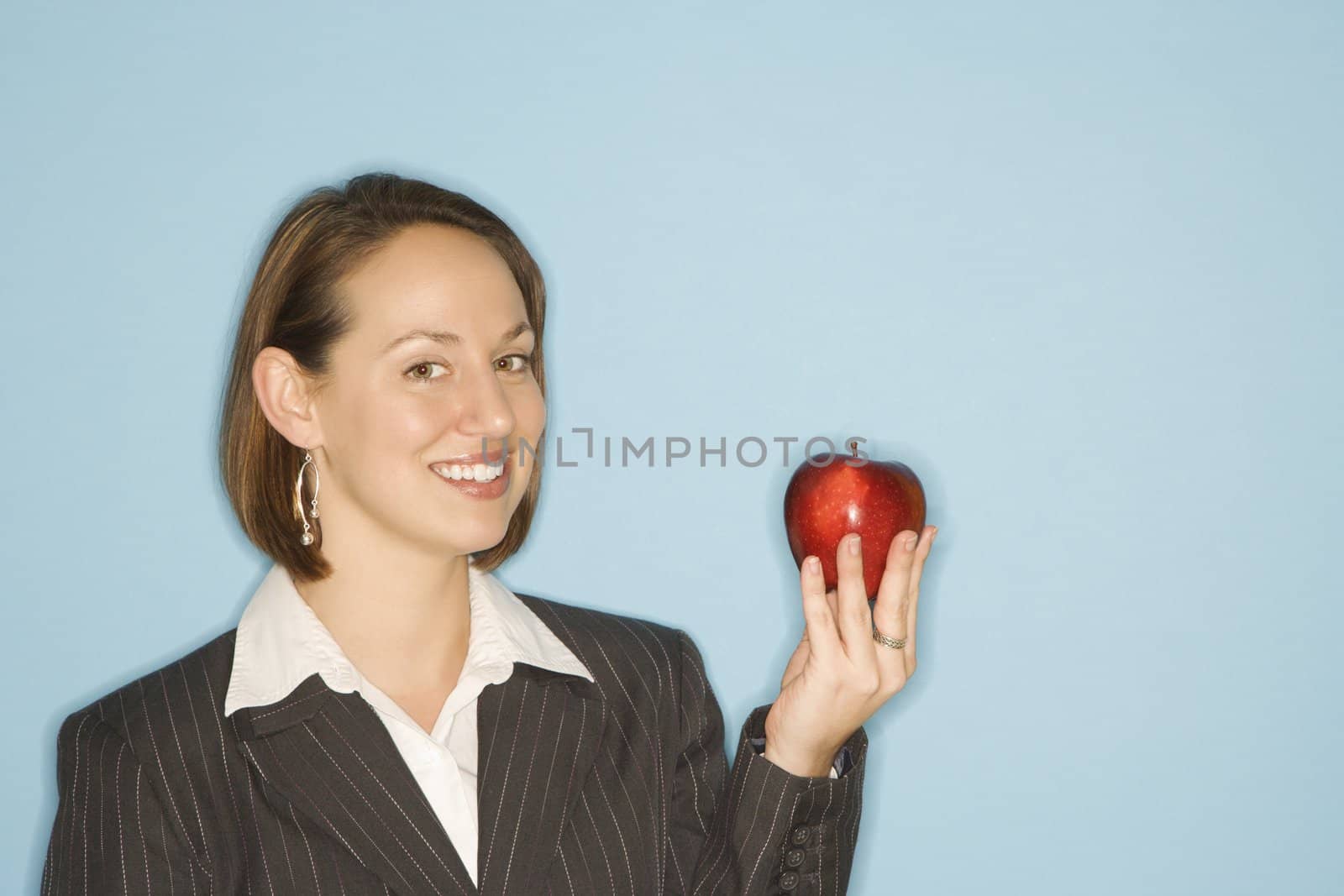 Caucasian businesswoman smiling holding red apple.