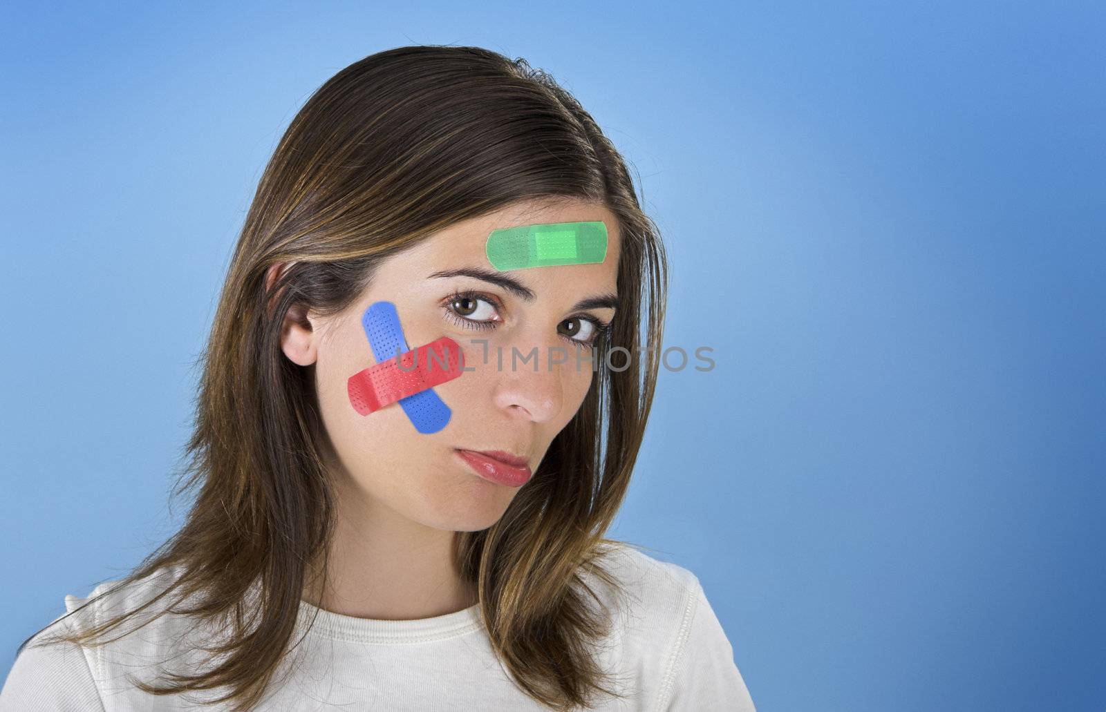 Beautiful woman with colored bandages on the face over a blue background