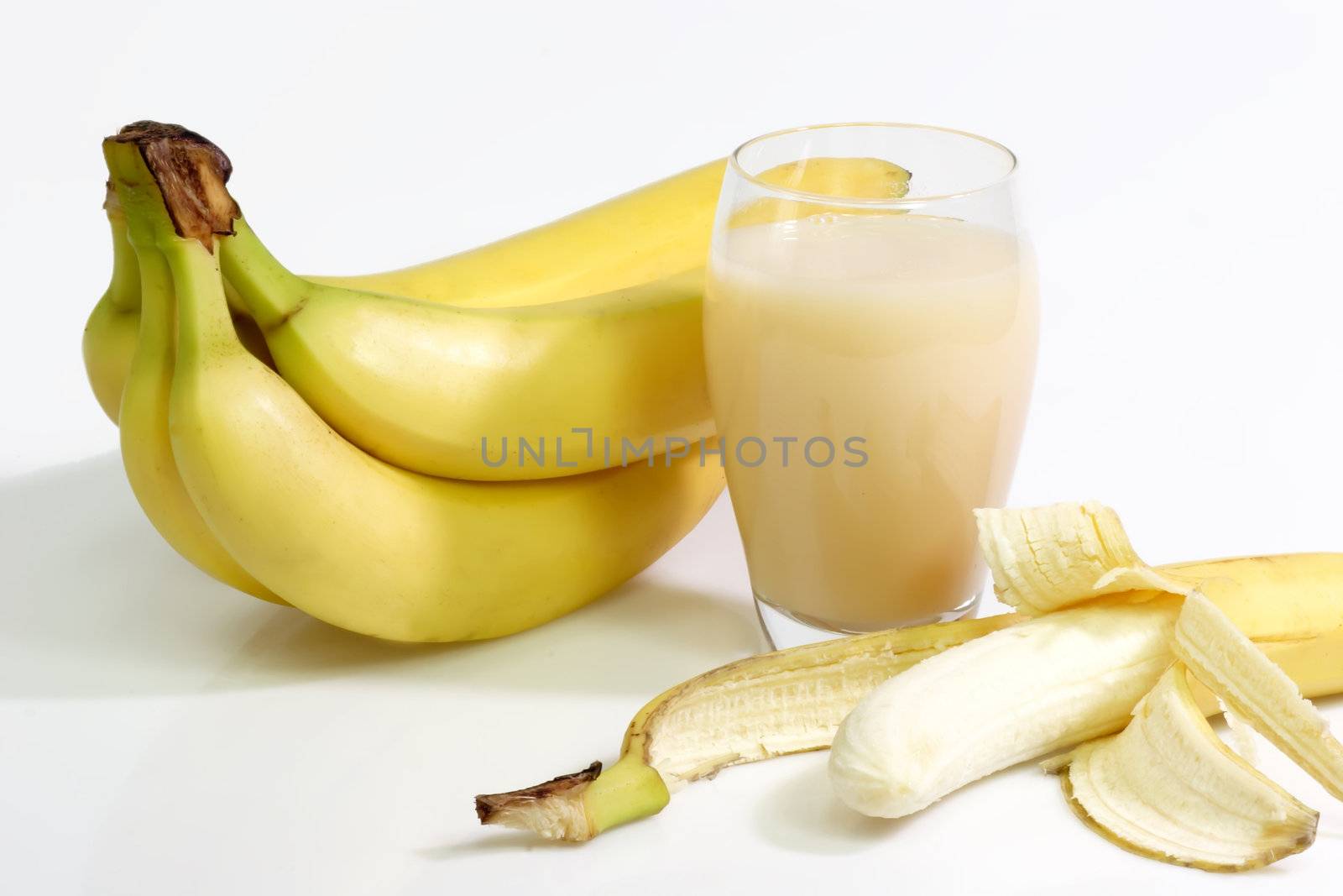 A glass of banana juice with fres bananas on bright background