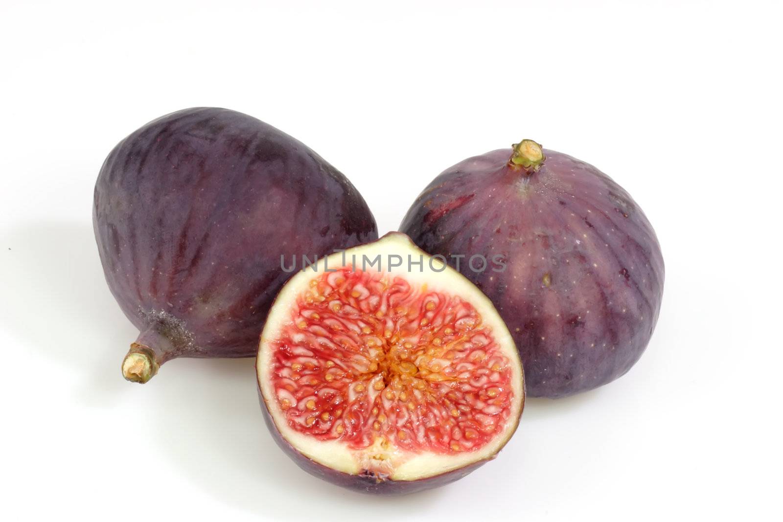 Two and a half ripe figs on bright background