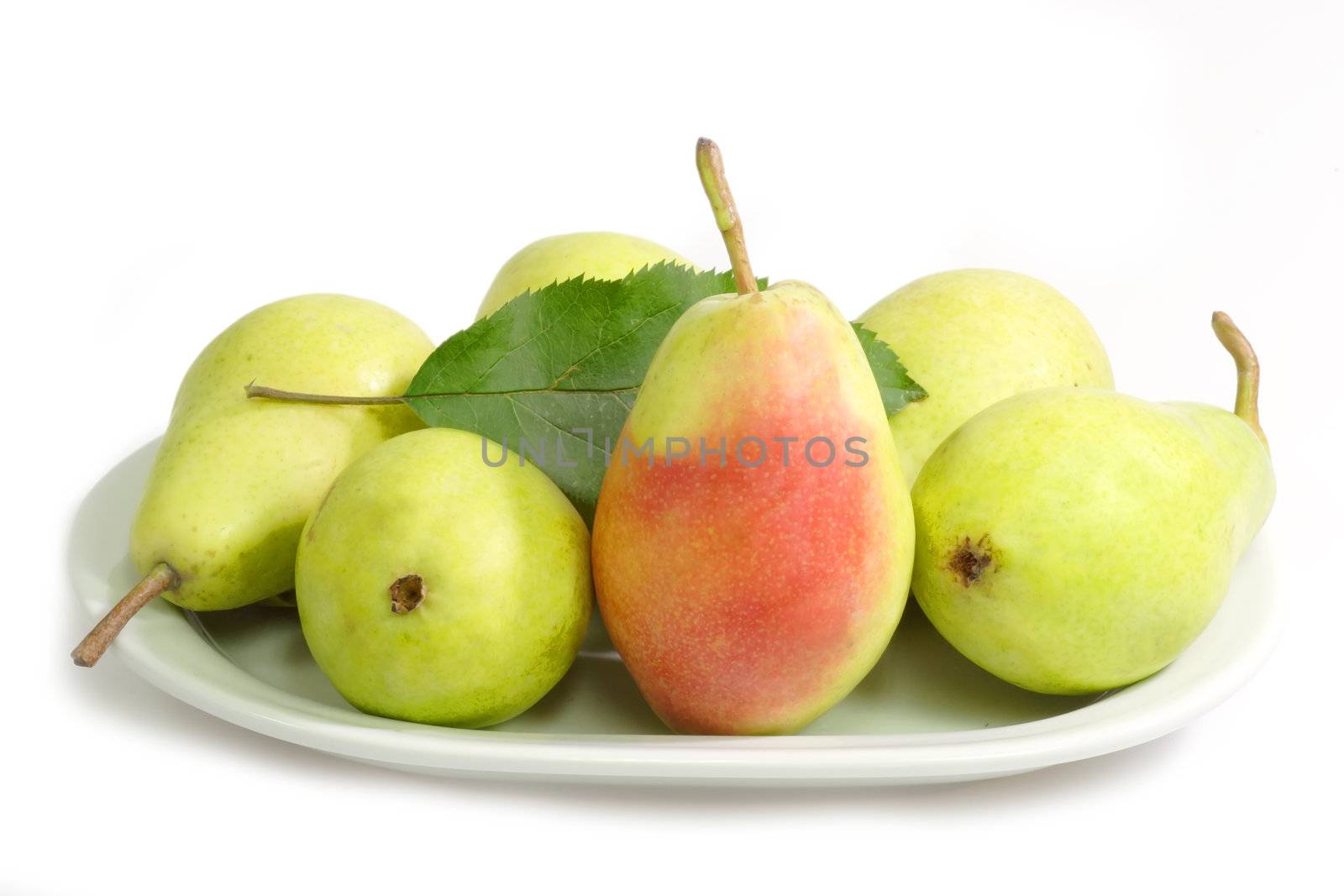 Fresh green pears on a plate on bright background