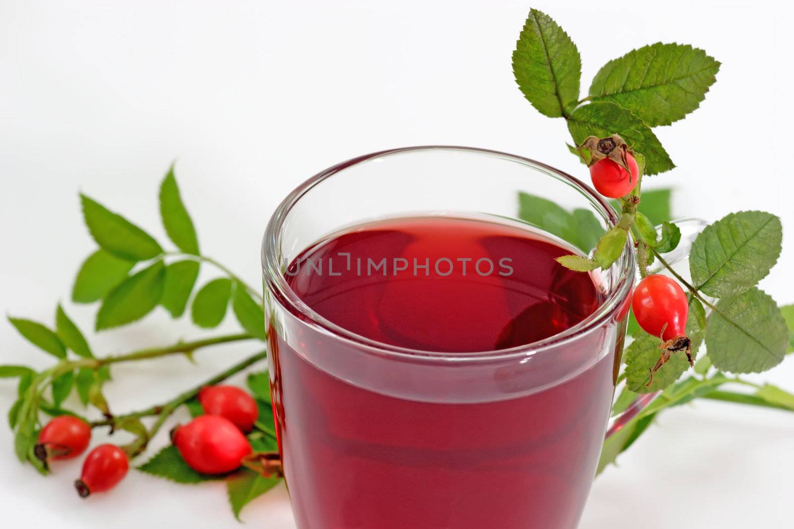 A glass of resehip tea with garnish on bright background